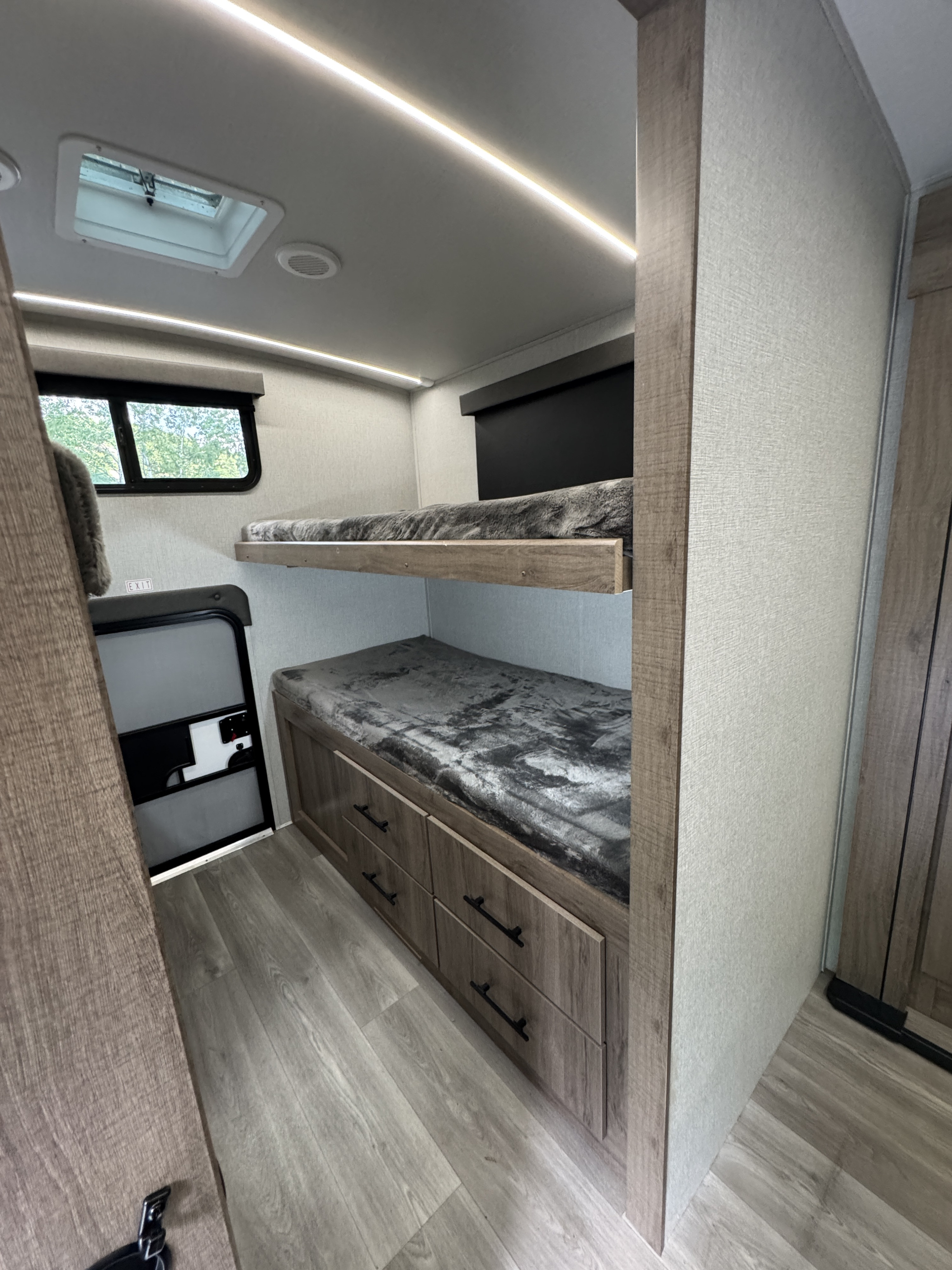 This RV rental offers practical bunk beds with under-bed storage, a window, and LED lights for comfortable travel.. Grand Design Imagine 2024
