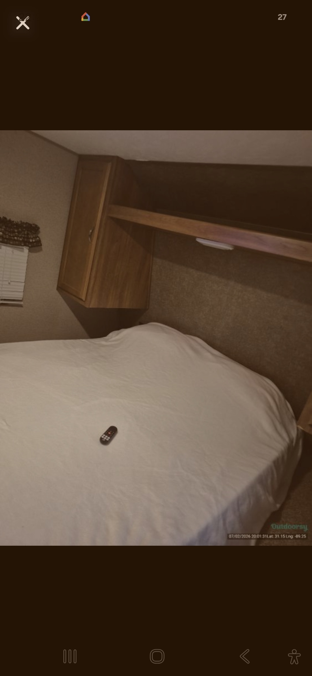 RV rental sleeping area features a comfortable bed with white sheets, overhead wooden cabinets, and a remote.. Keystone RV Summerland 2017