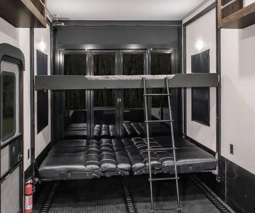 RV rental: Spacious toy hauler interior featuring a convertible lower bed/sofa, upper bunk bed, and diamond plate floor.. Keystone RV Raptor Toy Hauler 2021
