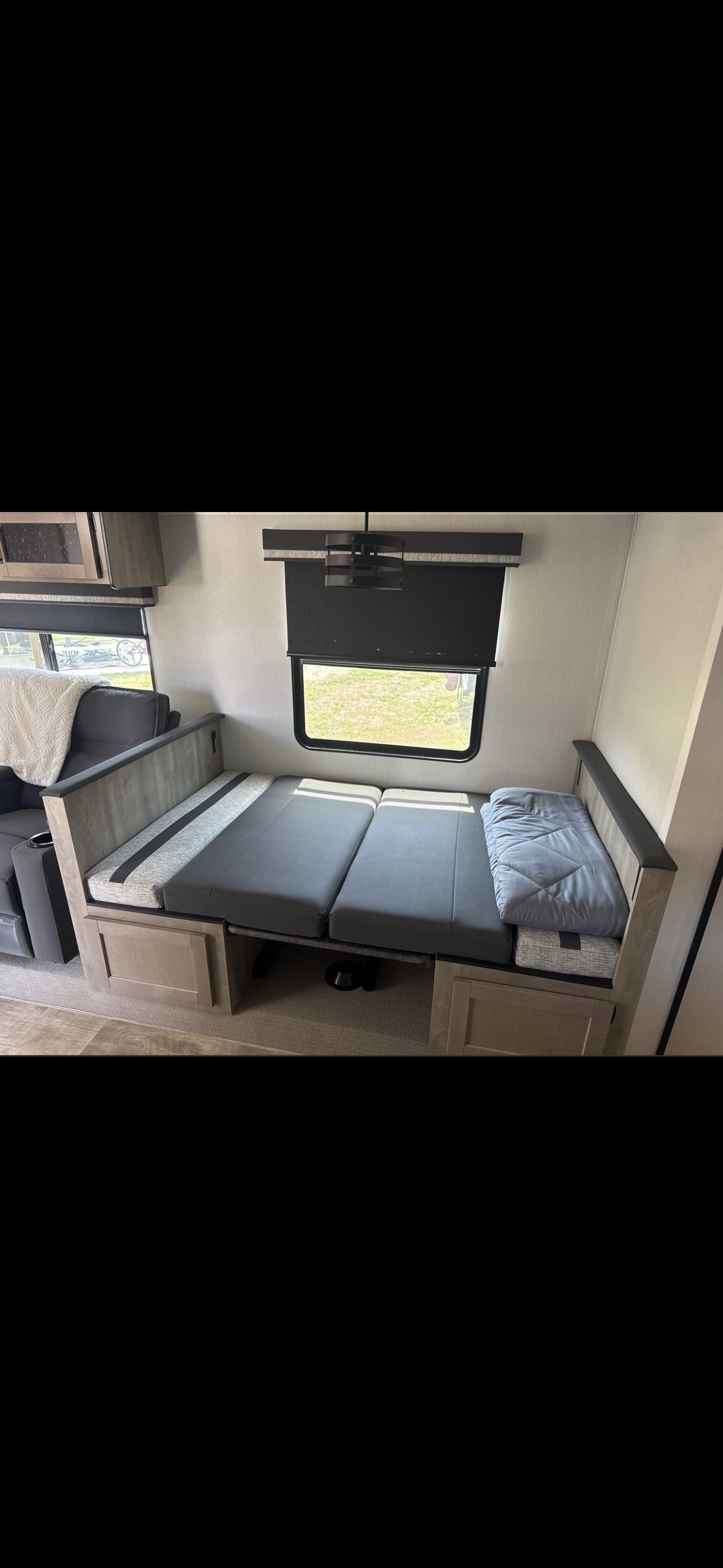 RV rental dinette seating converts to a bed, maximizing space in this neutral-toned interior with window views and storage.. Forest River Palomino Puma 2024