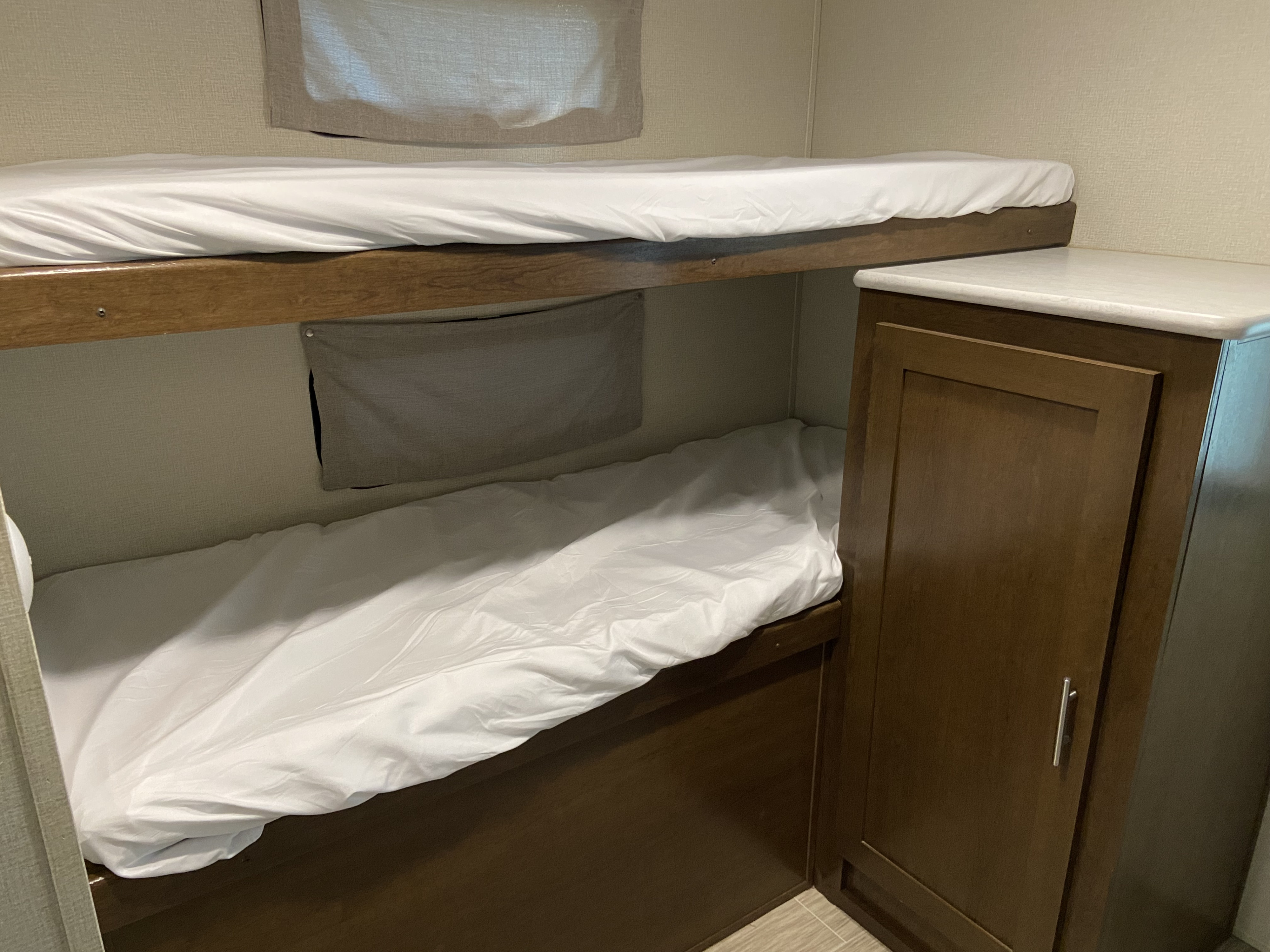RV rental interior featuring two bunk beds with white sheets and a built-in wooden cabinet, for compact sleeping.. Forest River Tracer Breeze 2019