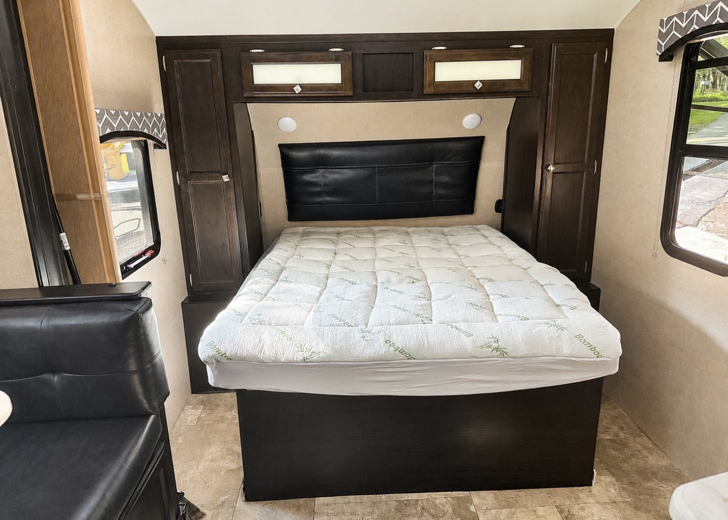 RV rental interior: A bedroom with a bed, black headboard, dark wood cabinetry, and a dinette area for comfortable stays.. Sonic Venture - SN220VBH 2018