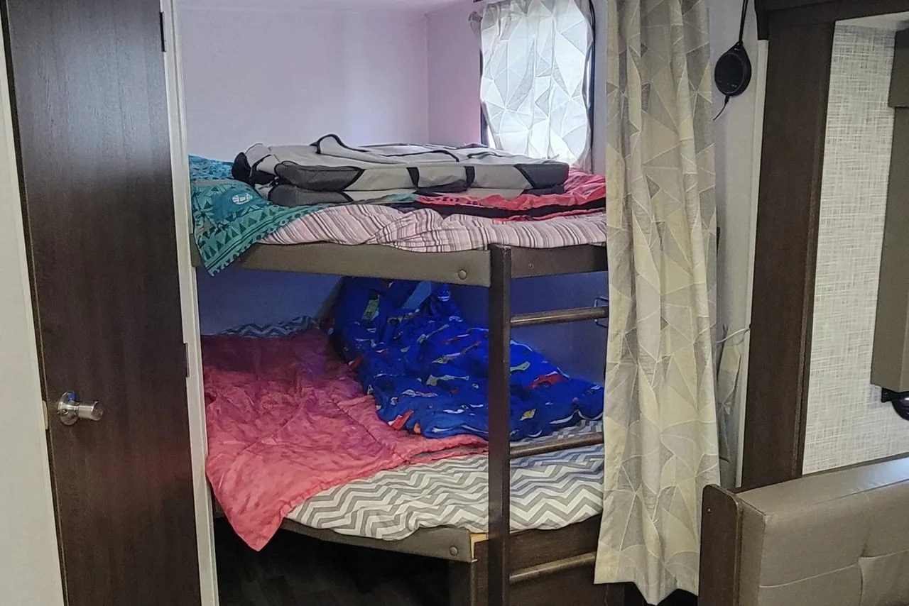 Bunk beds in an RV rental, featuring colorful blankets and curtains for a cozy sleep space.. Forest River Salem 2020