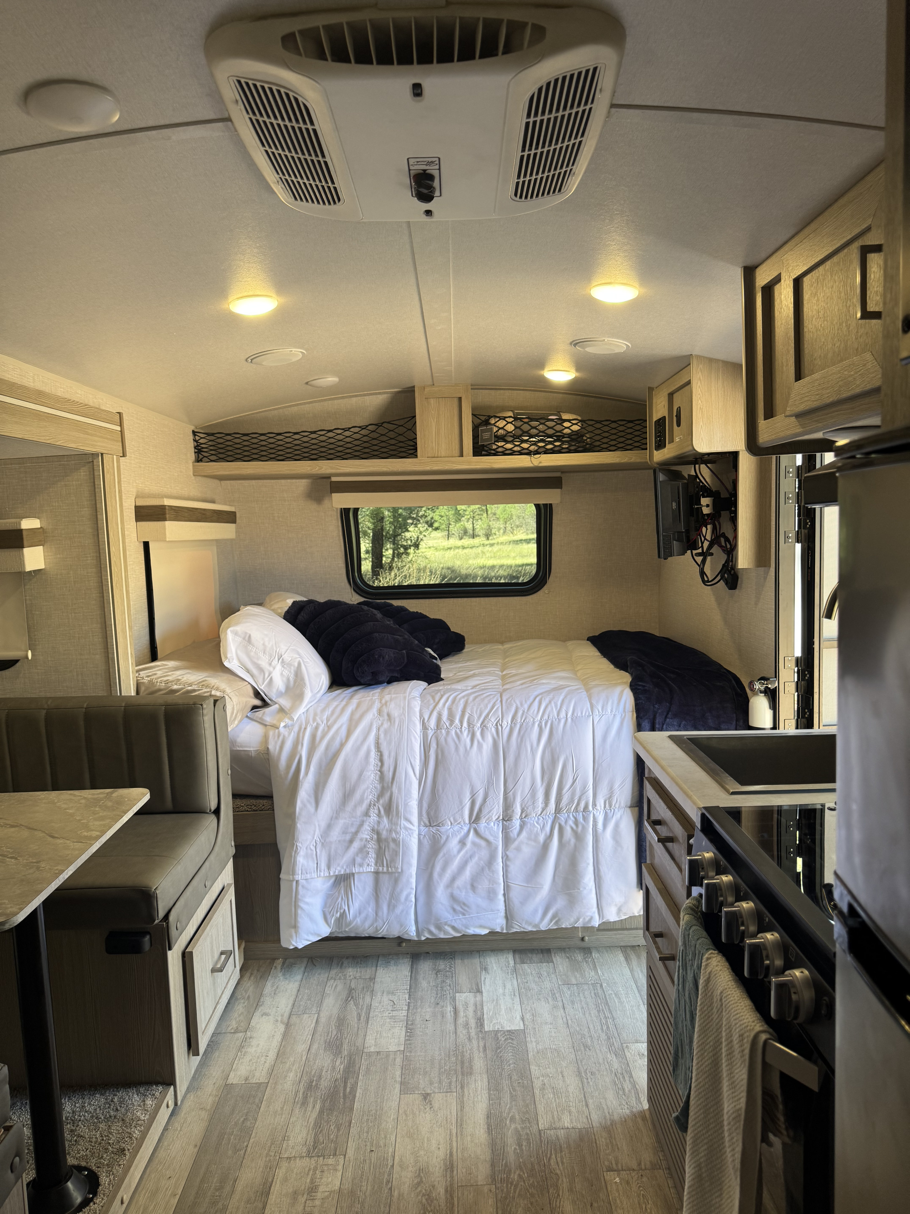 This RV rental offers a compact, cozy interior with a bed, dinette, kitchen, and scenic window view.. Forest River Rockwood Geo Pro 2022