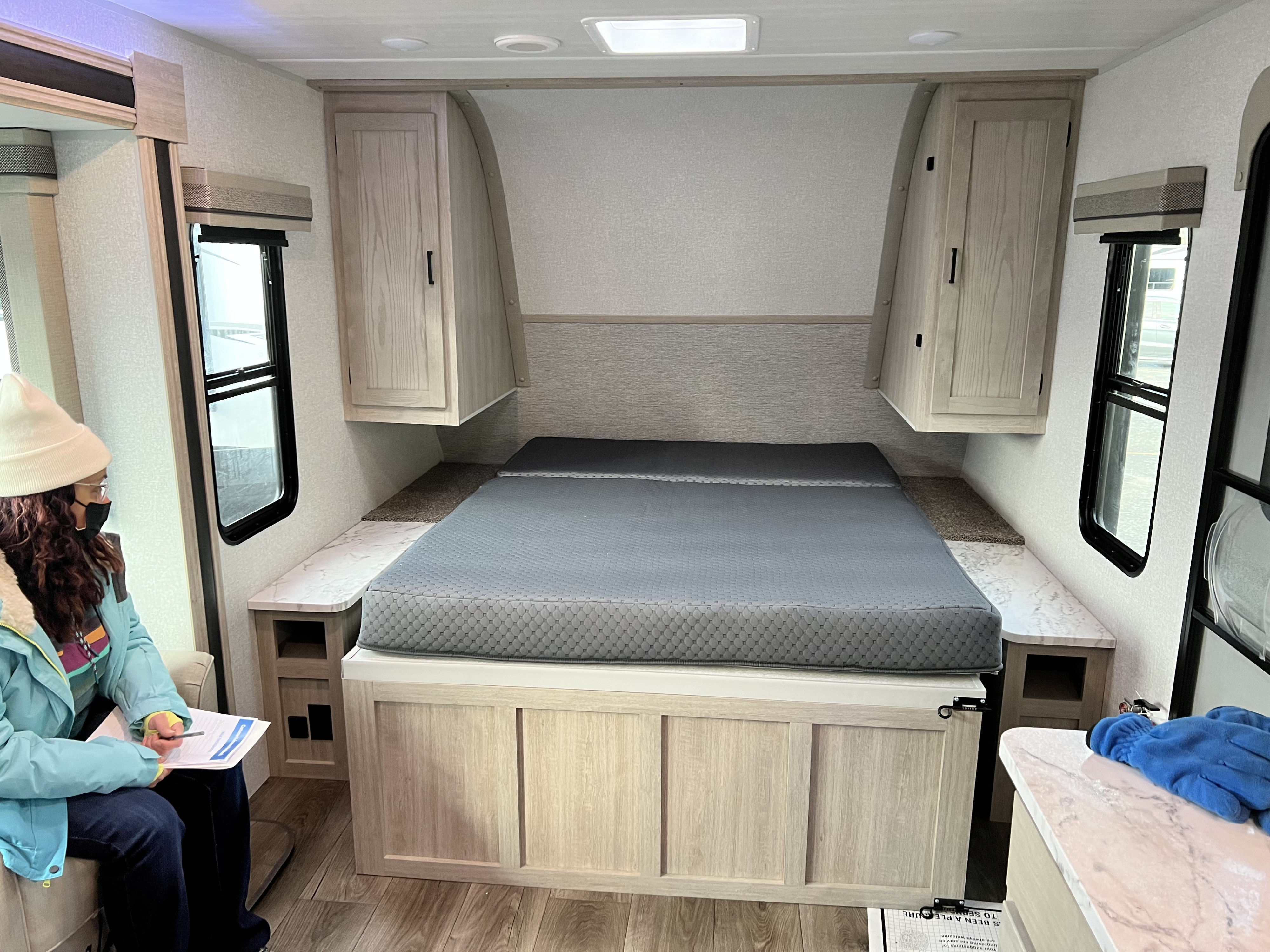 Inside a spacious RV rental bedroom featuring a queen bed, overhead cabinets, and side shelves.. East to West Alta 2022