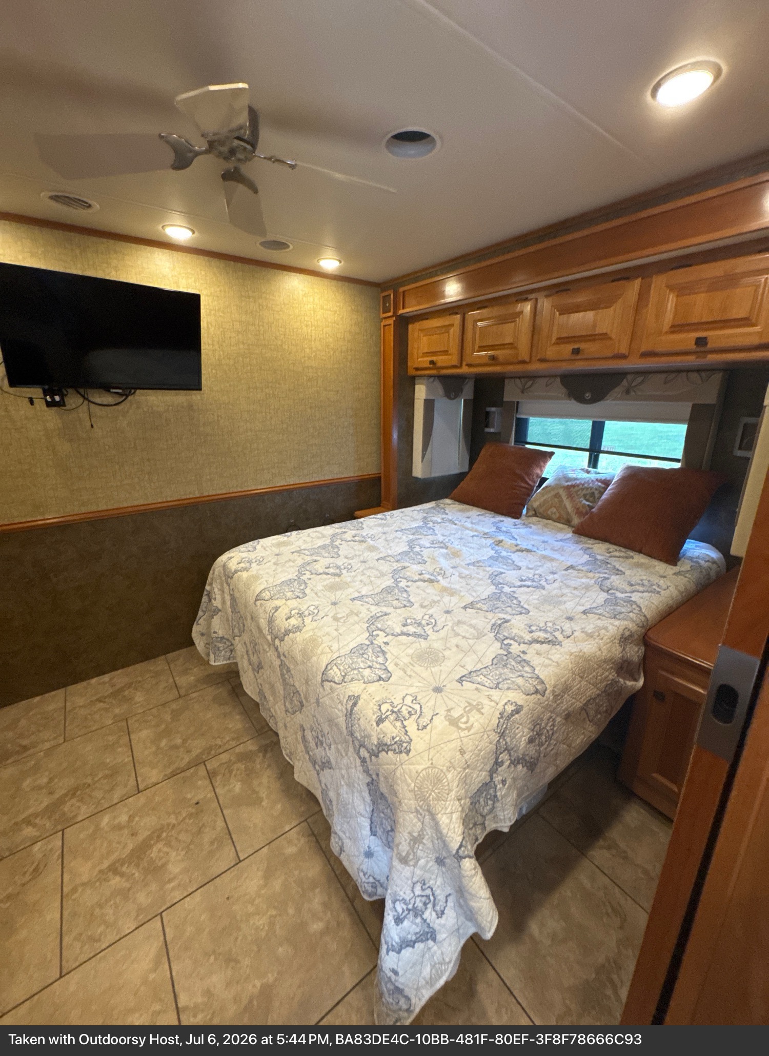 This RV rental bedroom features a comfortable bed, overhead storage, a wall-mounted TV, ceiling fan, and tiled floor.. Allegro Allegro Motorhome 2014