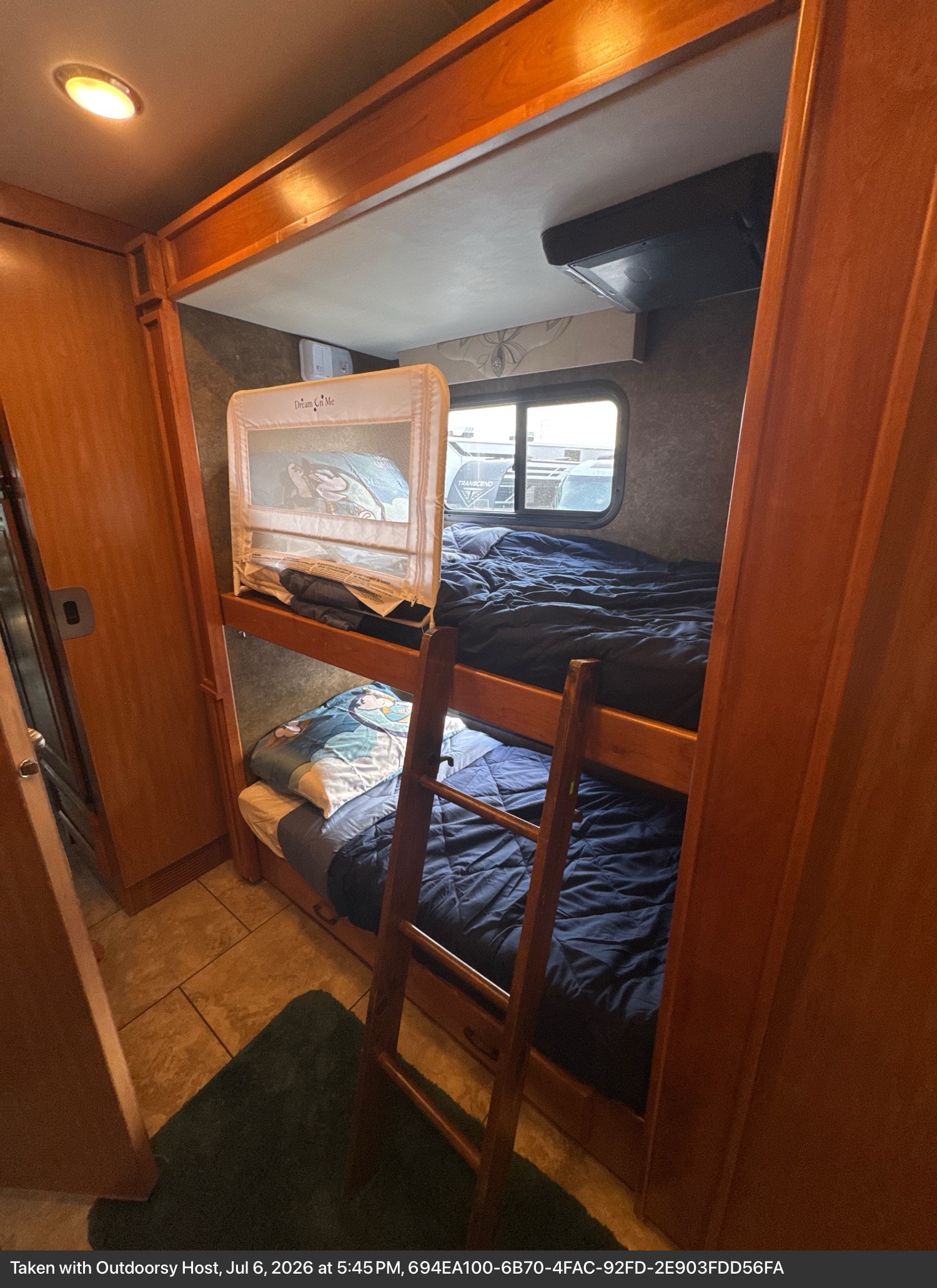 Interior view of an rv rental showing comfortable bunk beds with dark blue bedding, a safety rail, and ladder.. Allegro Allegro Motorhome 2014