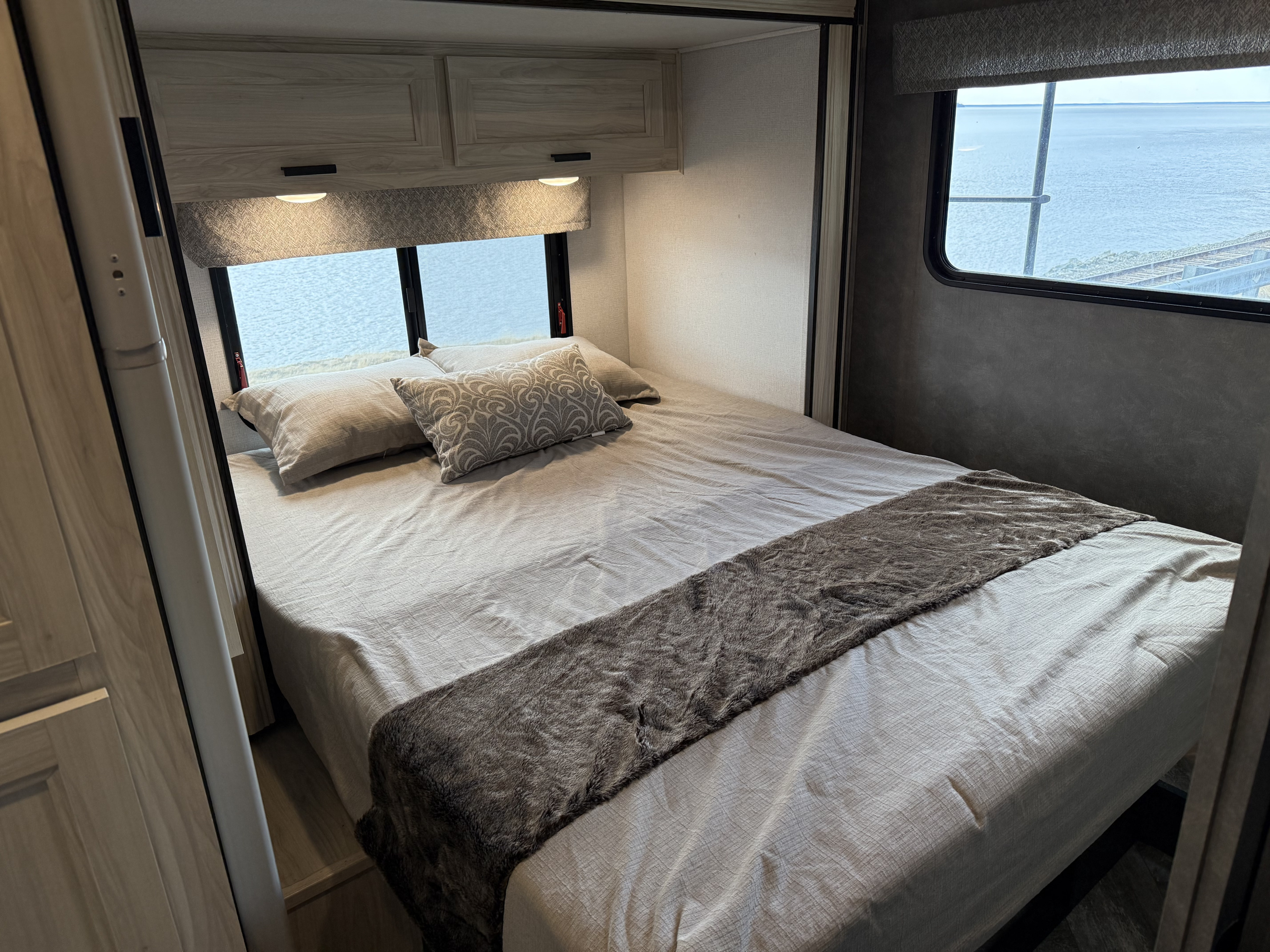 Spacious RV rental bedroom featuring a comfortable bed, light cabinetry, and a scenic water view with railroad tracks.. Forest River Forester 2551 DSLE 2022