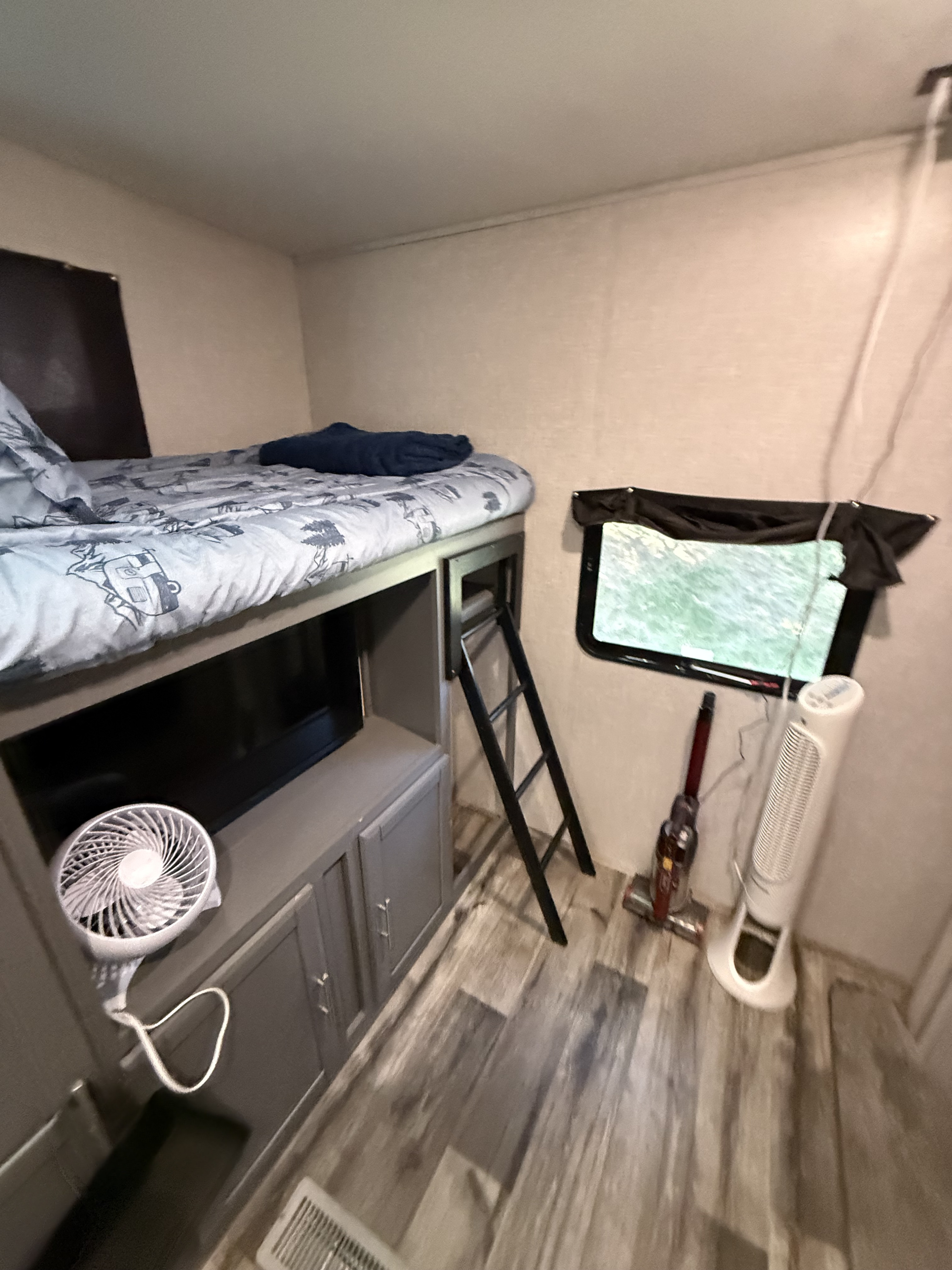 Cozy rv rental interior featuring a bunk bed, TV, ladder, window, portable fan, and stick vacuum.. Crossroads RV Volante 2022