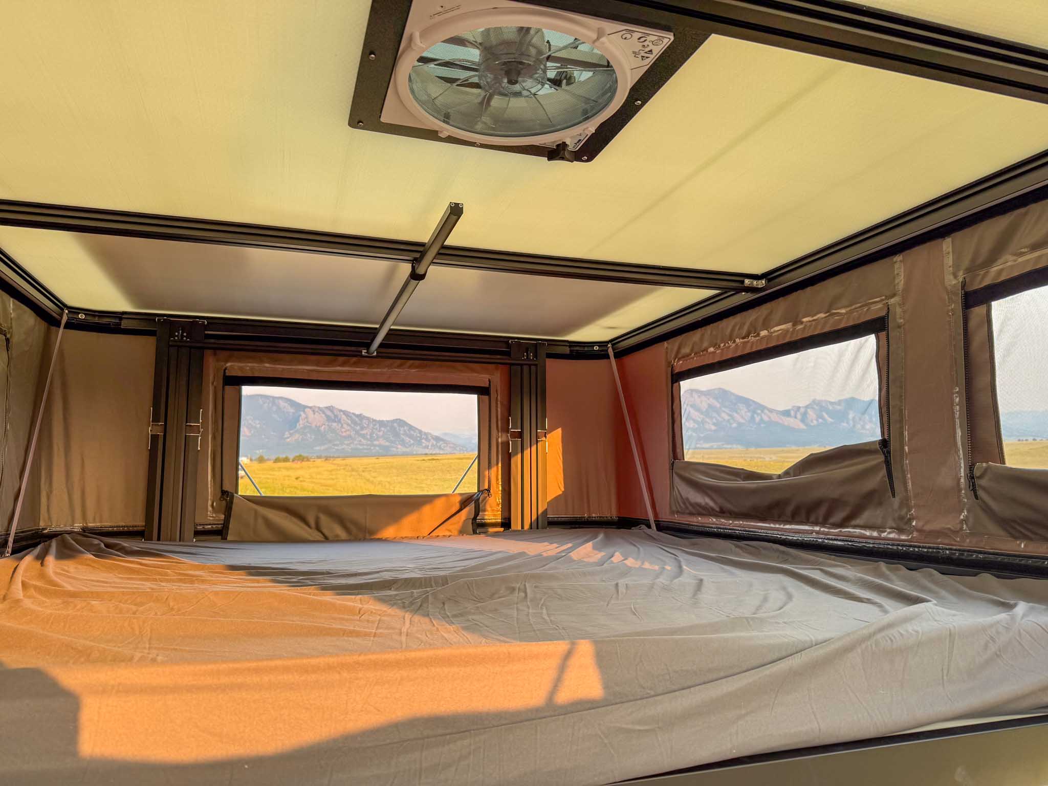 Inside this RV rental's rooftop tent: a comfortable bed, ceiling fan, and stunning mountain views await your camping adventure.. Toyota Tundra 2026