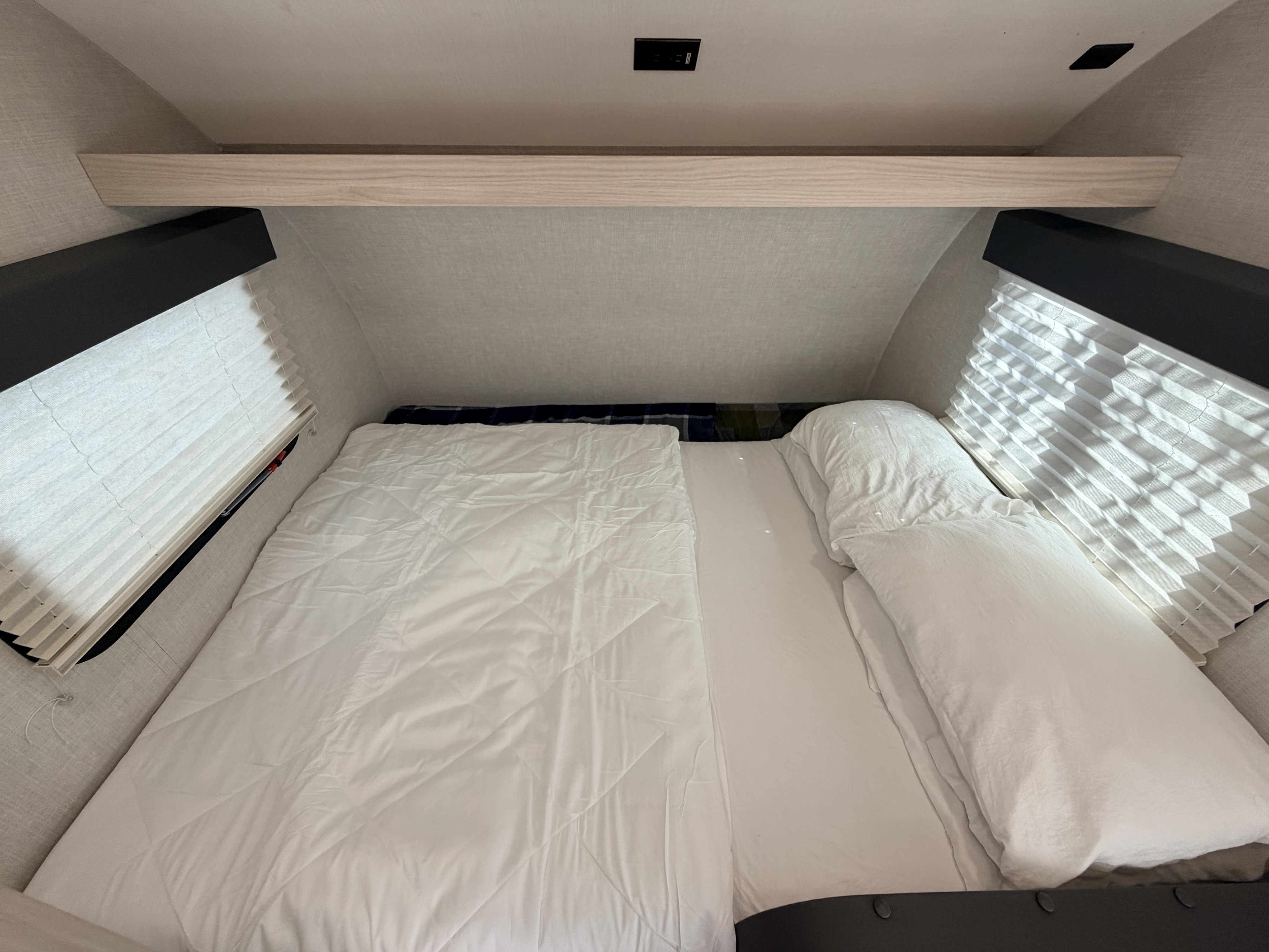Cozy RV rental bedroom with a comfortable bed, pillows, window blinds, and an overhead charging port, perfect for travel.. Winnebago Hike 2021