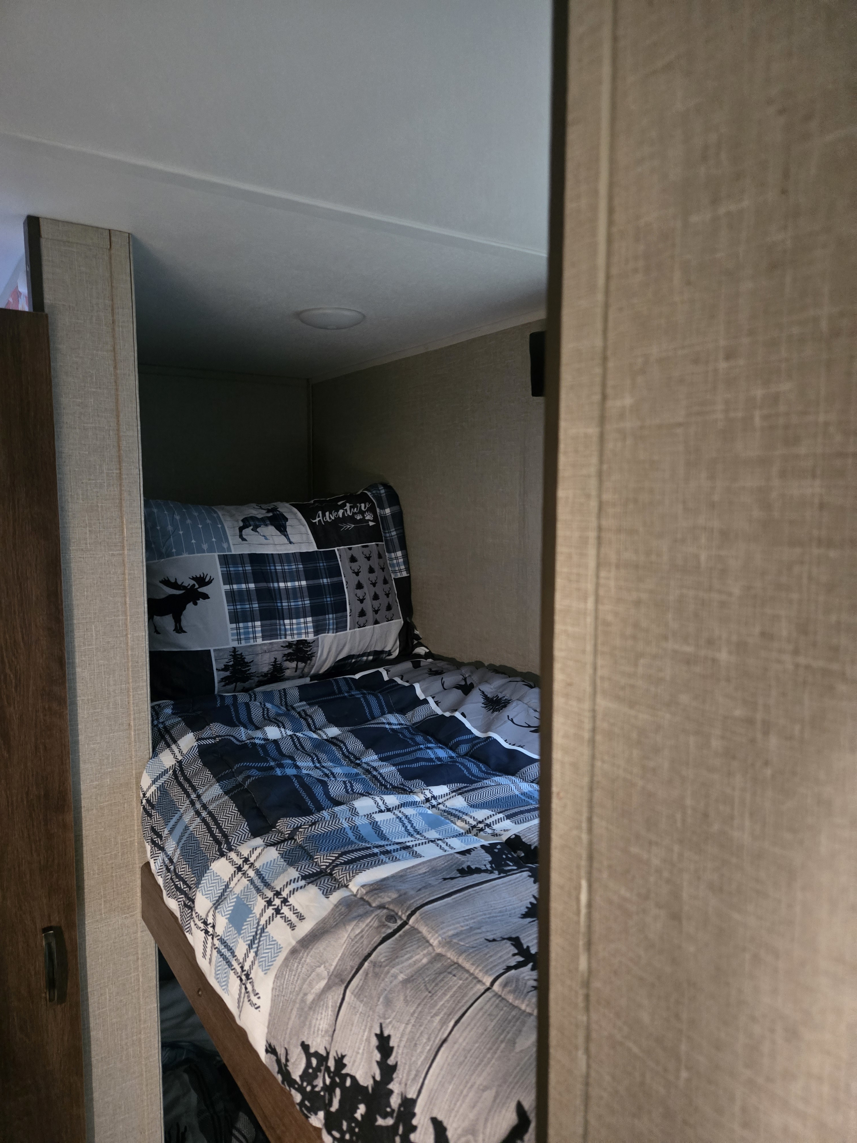 Cozy RV rental bunk bed with adventure-themed bedding, perfect for sleeping during your travels.. Travel Lite Falcon 2019