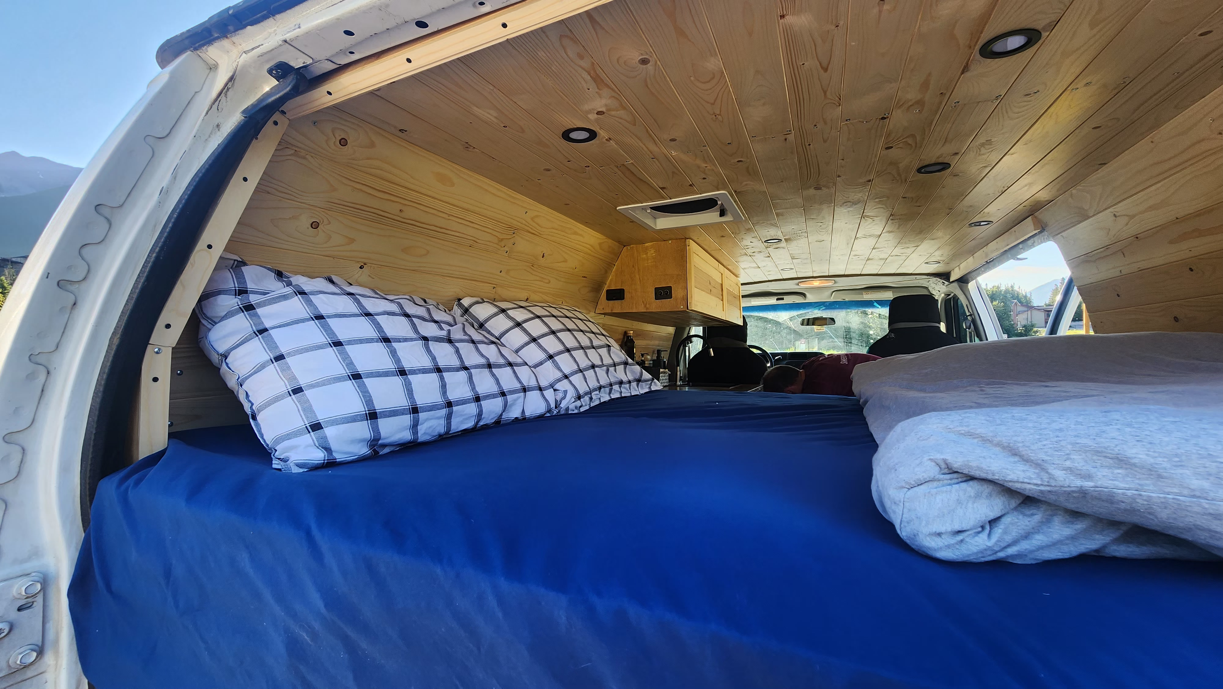 Experience comfort in this RV rental! Interior features custom wood paneling, a bed with blue sheets, and recessed lights.. Ford Econoline 2011