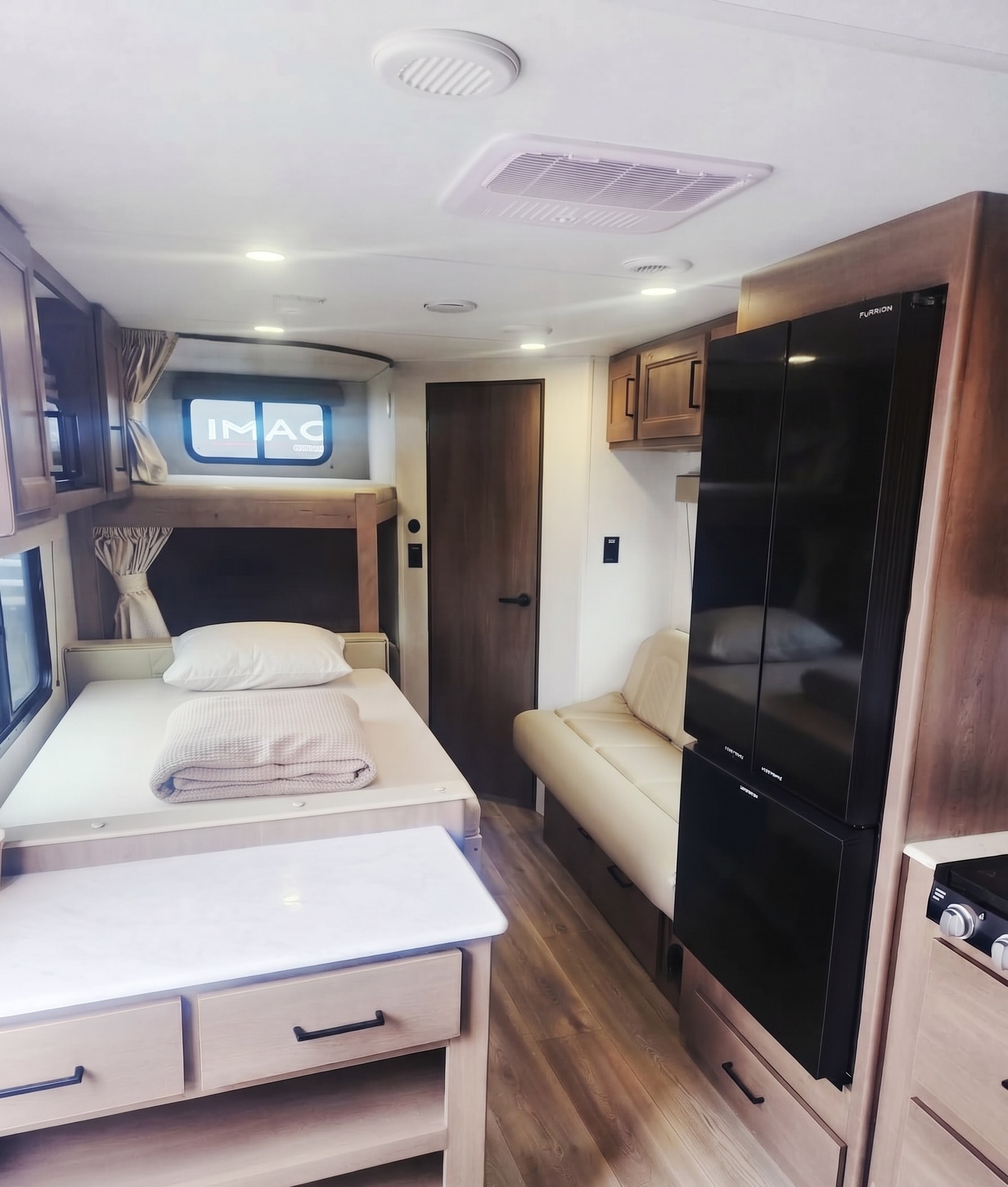 Spacious RV rental interior with bunk beds, kitchenette, sofa, and refrigerator, ideal for family adventures.. Grand Design Transcend Xplor 2025