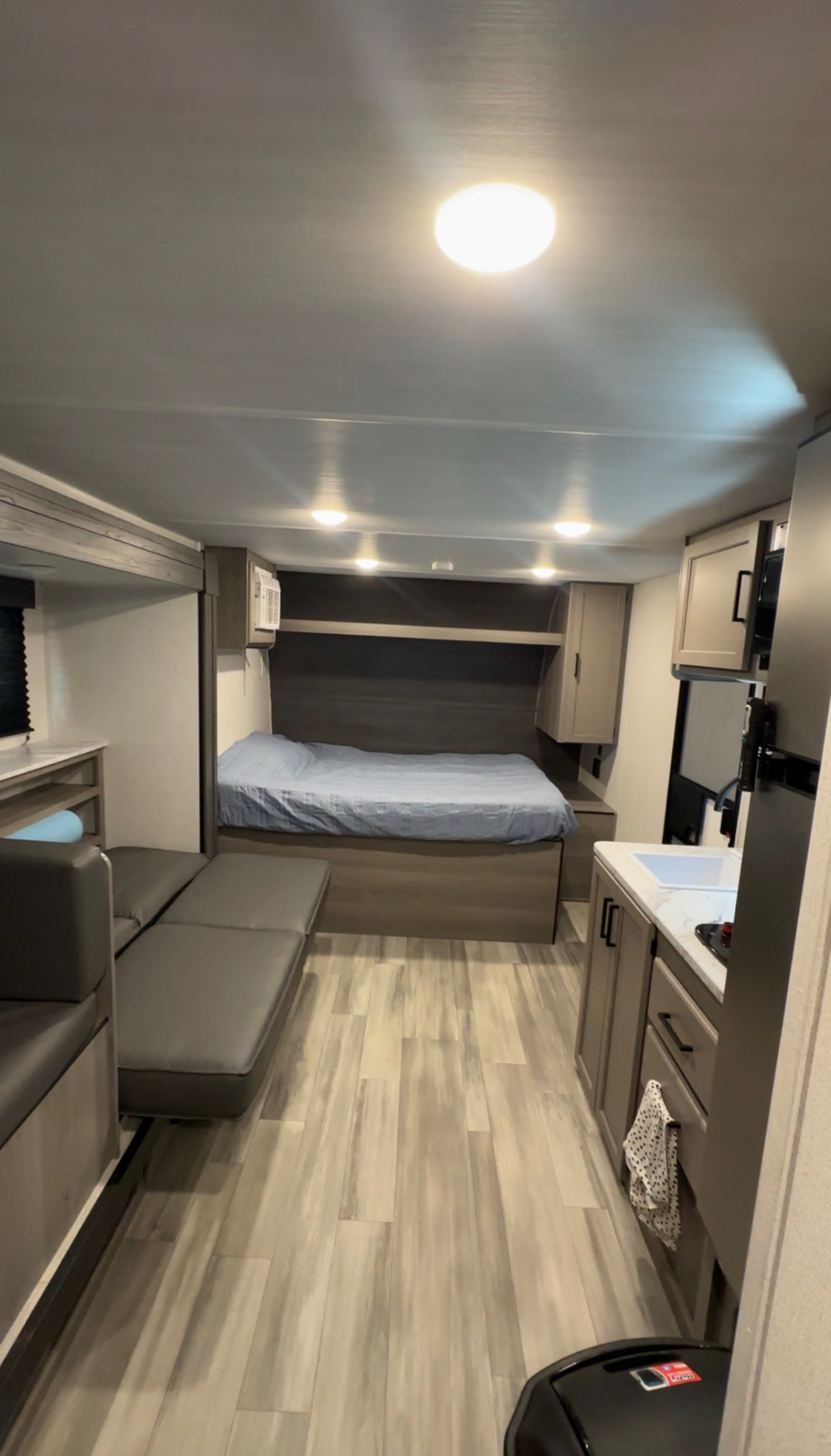 Inside an RV rental: modern interior featuring a cozy bed, convertible dinette, and compact kitchen. Light-toned flooring.. Keystone RV Hideout Sport 2024