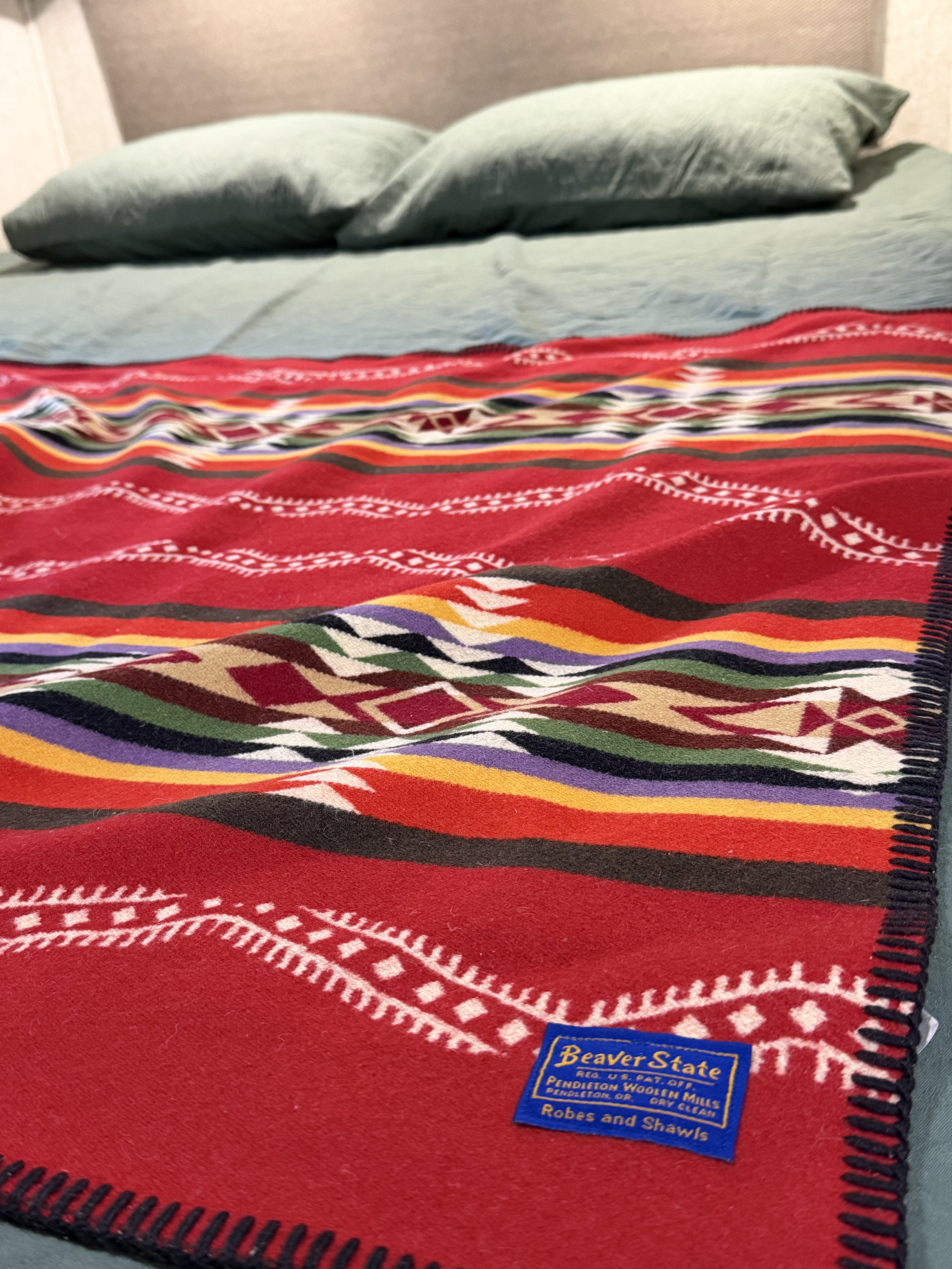 Vibrant red Pendleton blanket with geometric patterns on a bed, perfect for an rv rental. Adds warmth and color.. Forest River Sunseeker LE 2021