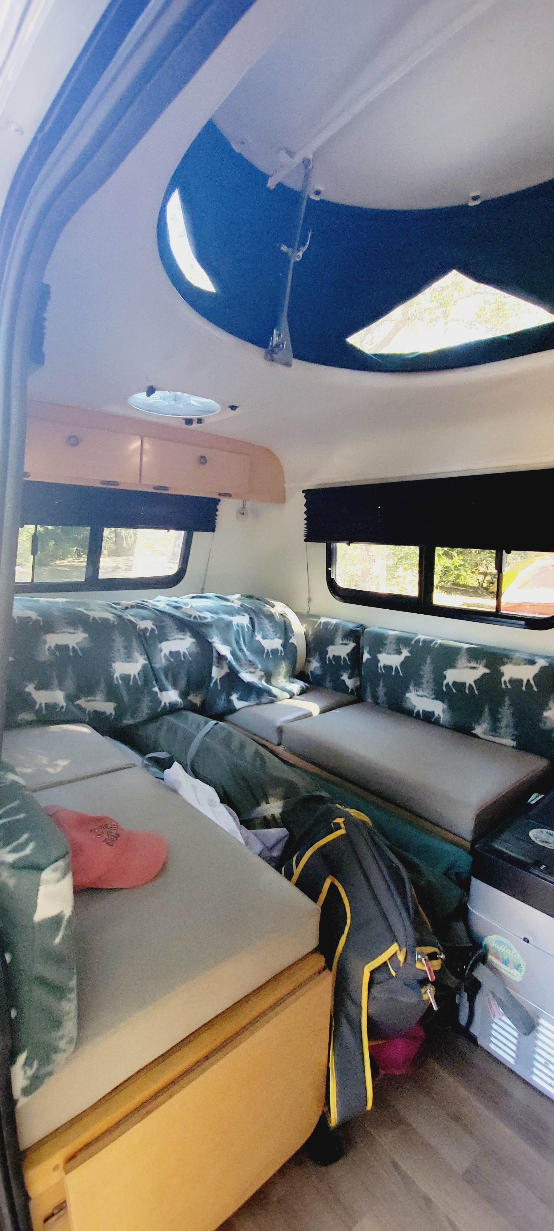 Cozy RV rental interior: a camper's sleeping area with deer blanket, overhead storage, and scenic windows.. Little Guy Little Guy Trailer 2018