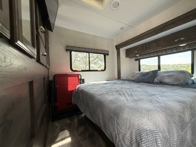 Cozy rv rental bedroom with a large bed, scenic window views, and modern wood-paneled walls. Enjoy comfortable travel.. Gulf Stream Conquest 2023