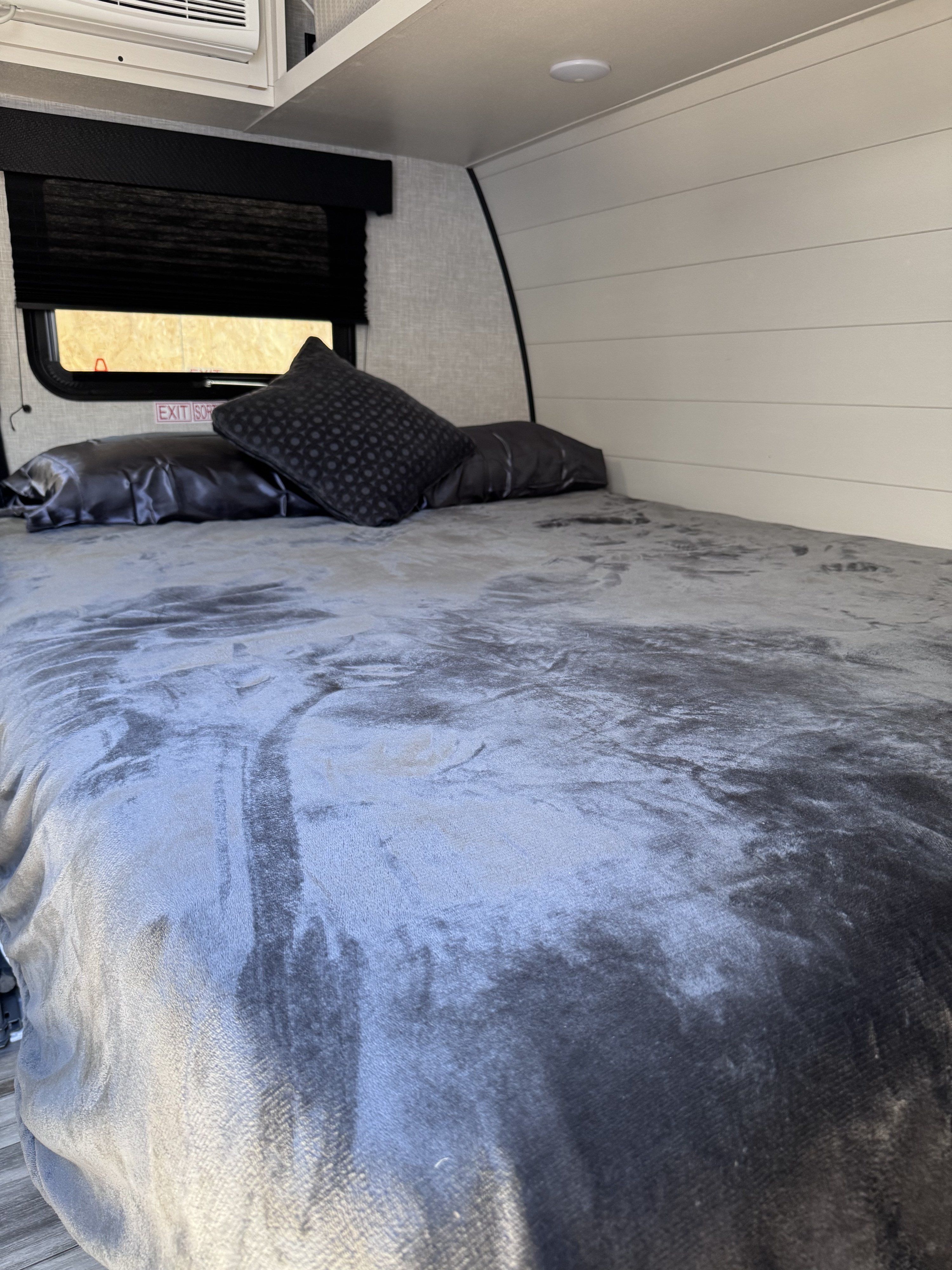 RV rental bedroom with a cozy bed, dark pillows, a window, and an air conditioning unit for comfortable travel.. Jayco Jay Flight 2025
