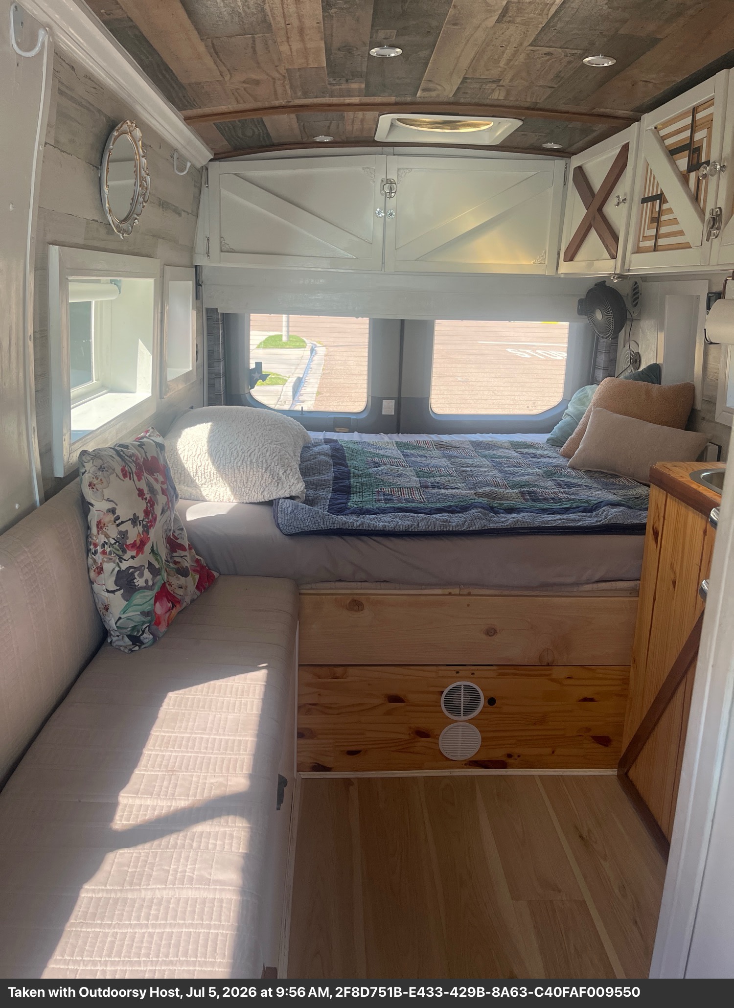 Cozy RV rental interior featuring a comfortable bed, sofa, rustic wood ceiling, and overhead storage cabinets.. Ford T-350 Transit Wagon 2016
