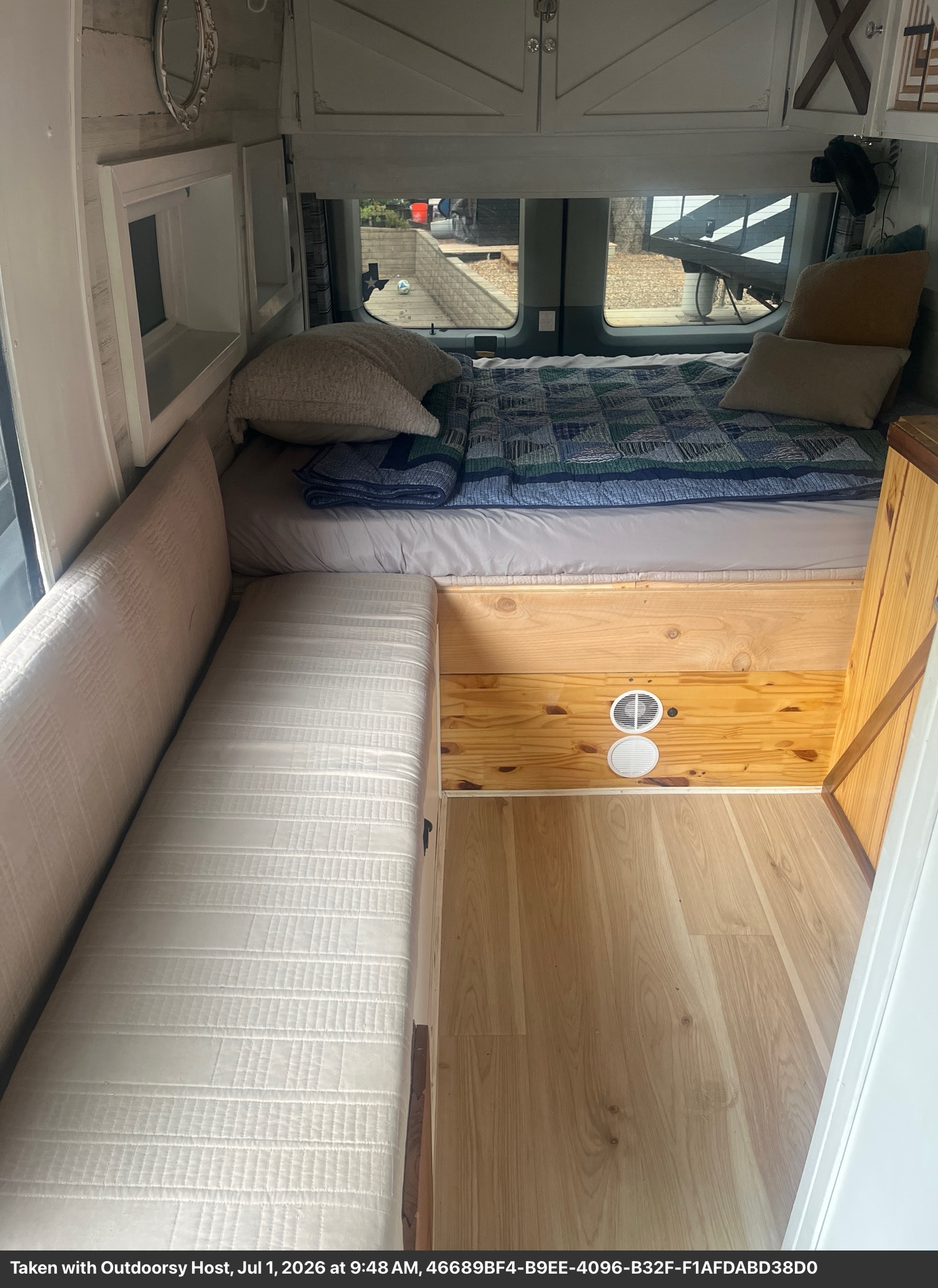 Cozy RV rental interior featuring a comfy bed, bench seating, and warm wooden accents, ideal for van life adventures.. Ford T-350 Transit Wagon 2016