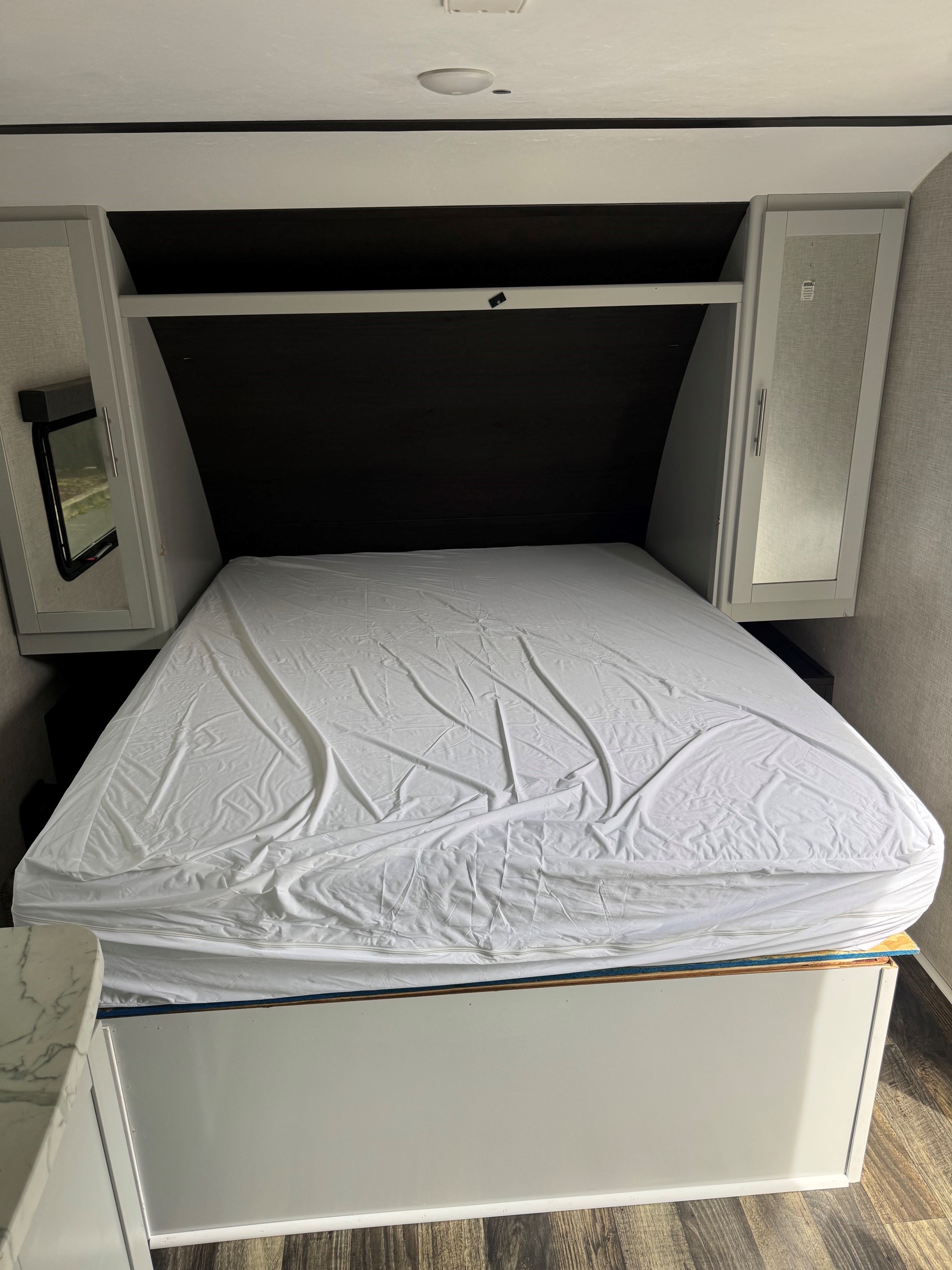 RV rental bedroom with a neatly made bed, overhead storage, and side cabinets, offering a compact and cozy interior space.. Keystone RV Bullet Crossfire 2020
