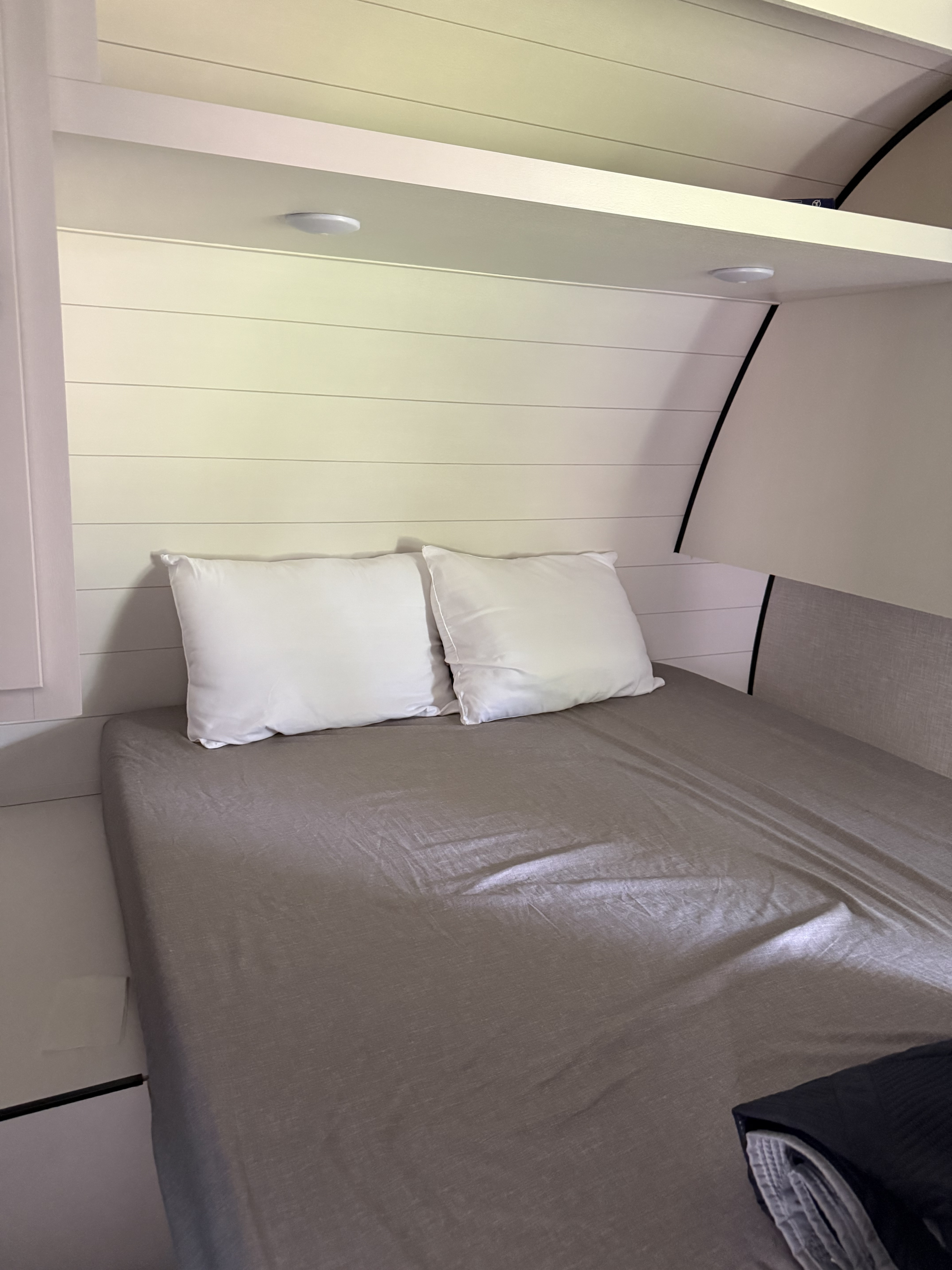 RV rental bed nook with white pillows, gray sheets, and overhead shelf lighting, perfect for a cozy night.. Jayco Jay Flight SLX 2024
