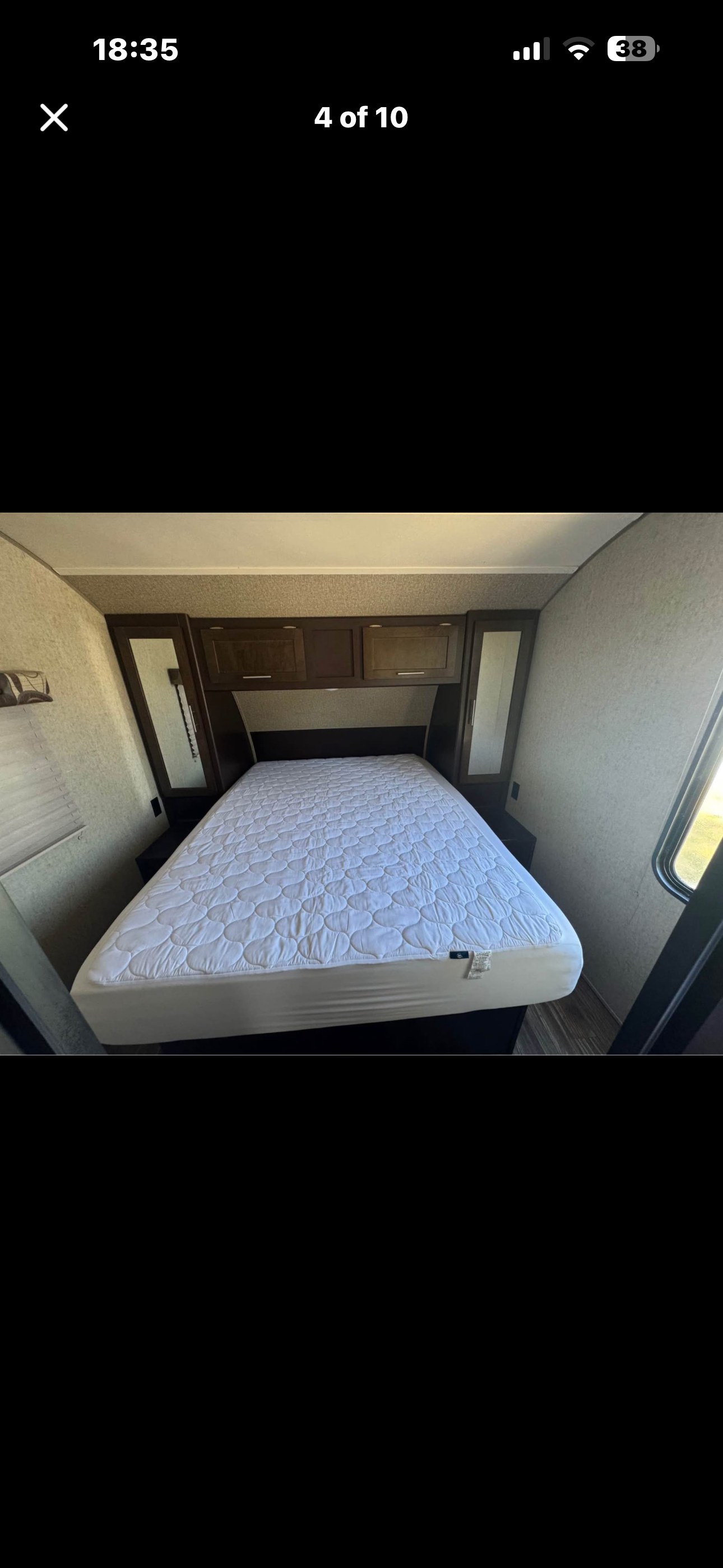 RV rental bedroom features a comfortable bed with a quilted mattress pad, overhead storage, and side mirrors.. Forest River Cherokee Grey Wolf 2016