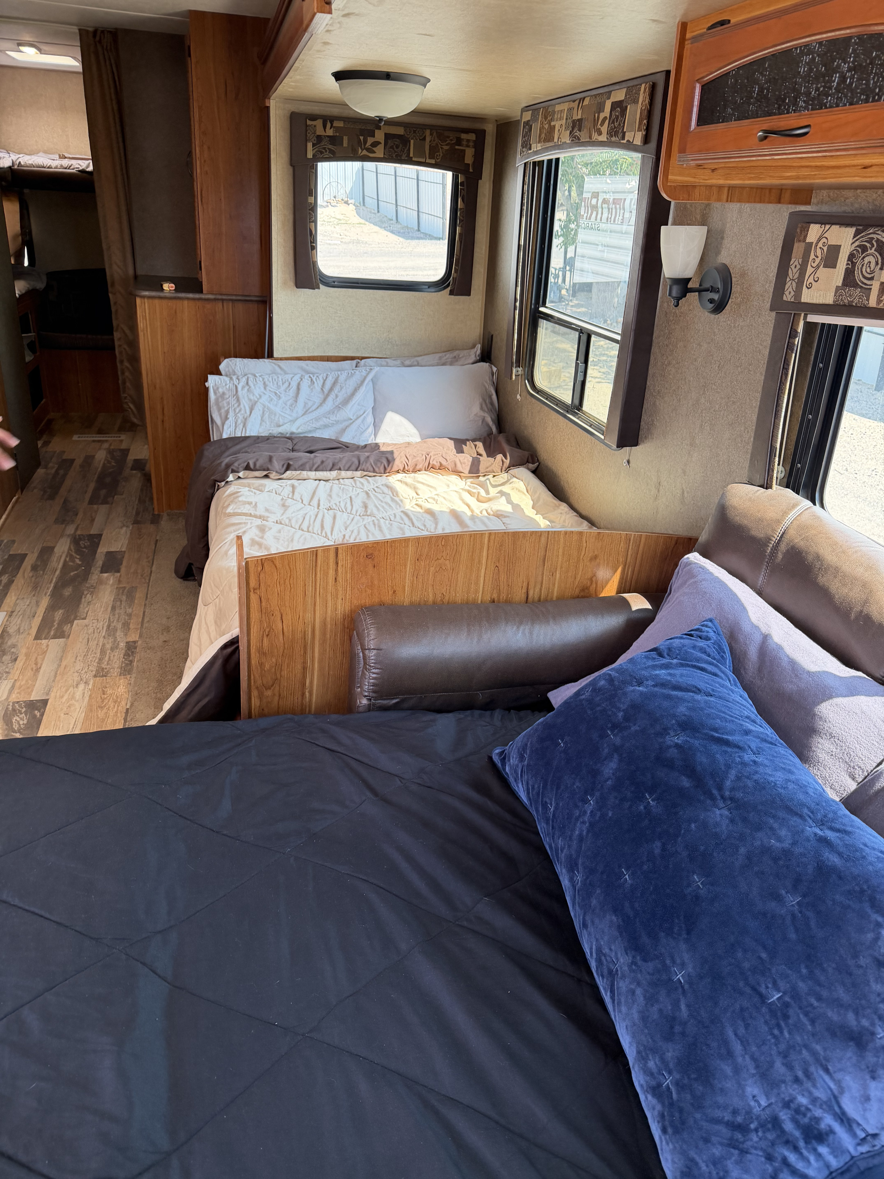 This inviting RV rental interior features multiple sleeping areas: a main bed, bunk beds, and a sofa bed in the foreground.. Starcraft Autumn Ridge 2015