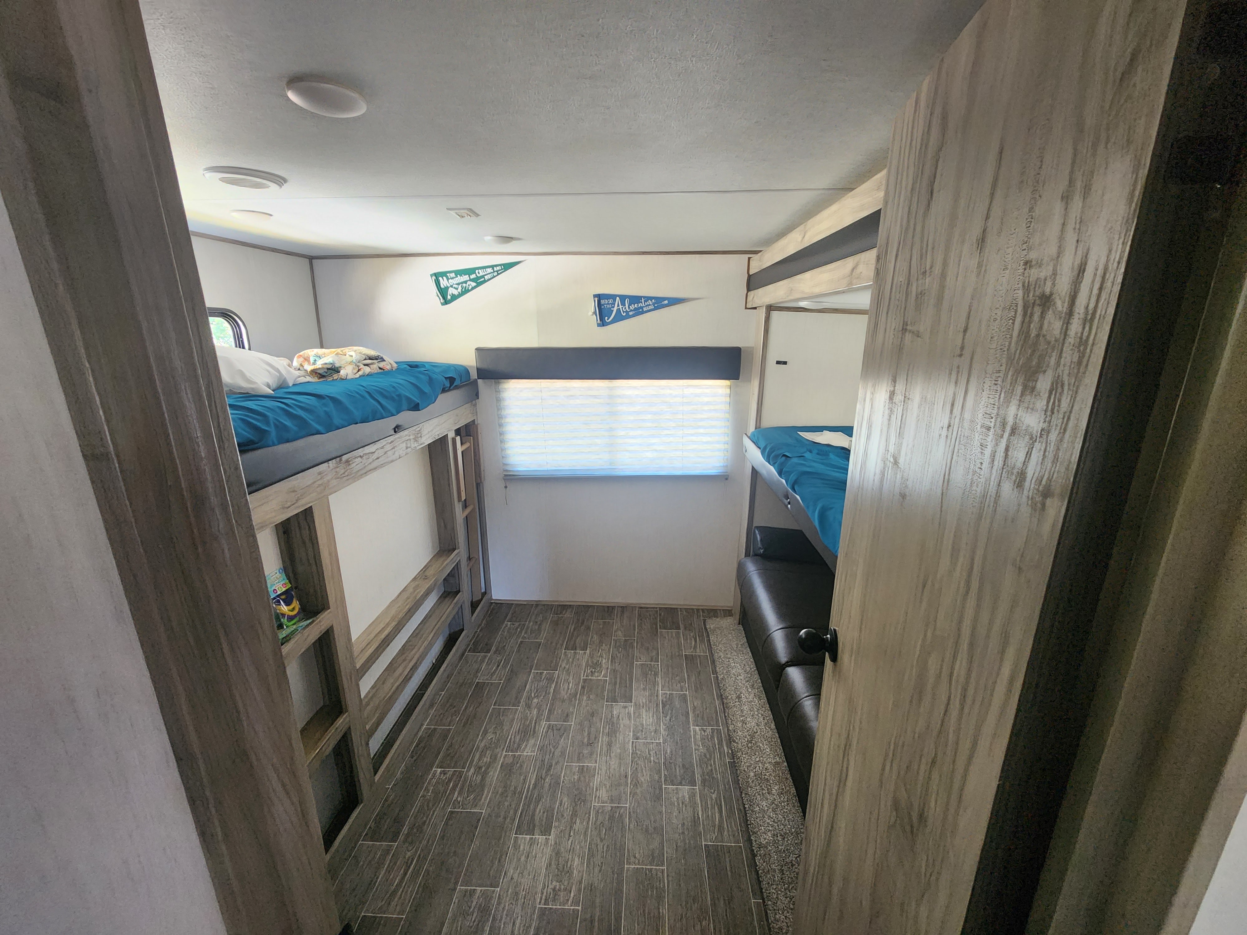 Cozy RV rental interior with bunk beds, perfect for family adventures. The compact space features wood-look floors and wall decor.. Forest River Cherokee Alpha Wolf 2021