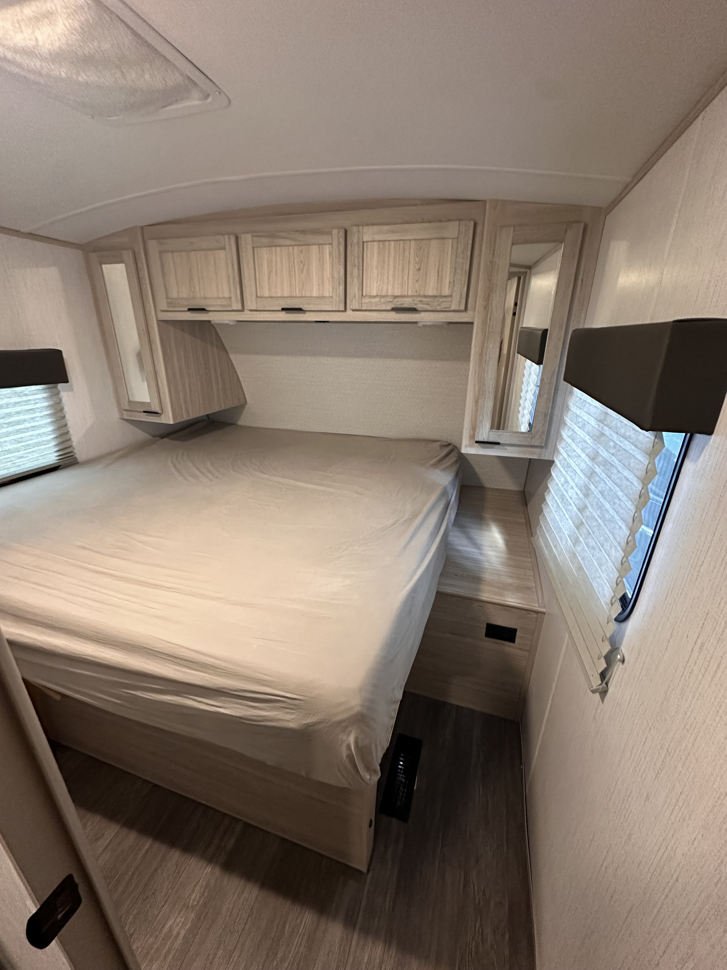 Cozy RV rental bedroom showing a bed, overhead cabinets, and window blinds on wood-look flooring.. Crossroads RV Shadow Cruiser 2022