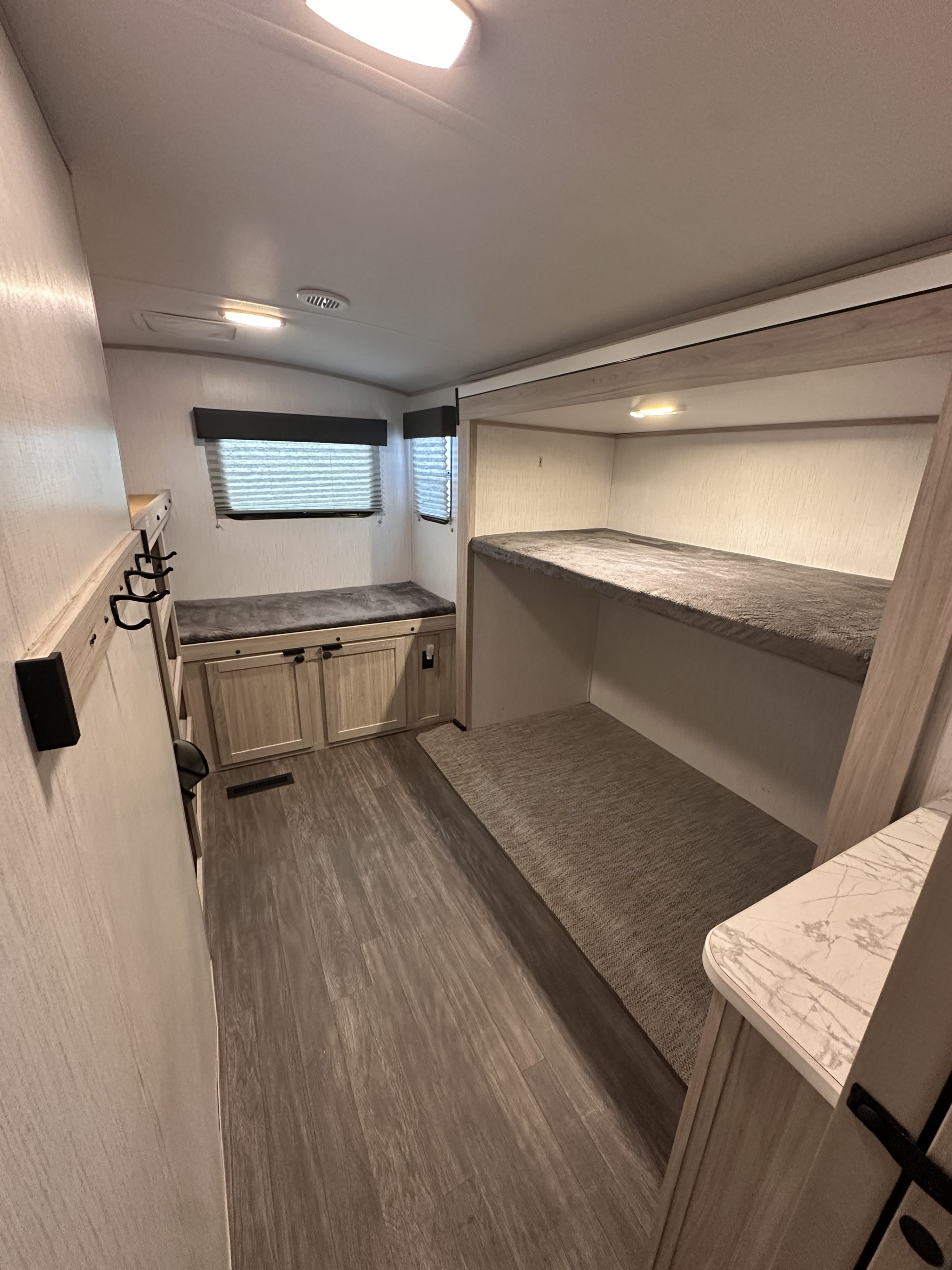 Inside an RV rental: a compact sleeping area featuring bunk beds, bench seating with storage, and laminate flooring.. Crossroads RV Shadow Cruiser 2022