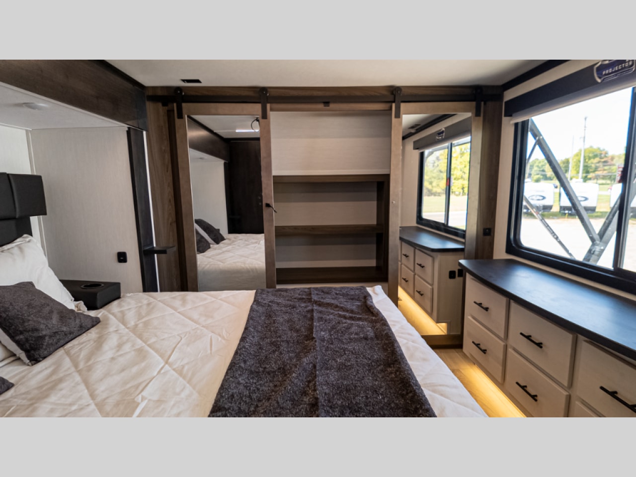 Experience comfort in this modern RV rental bedroom featuring a large bed, mirrored closet, ample storage, and wide windows.. Forest River Vengeance 2022