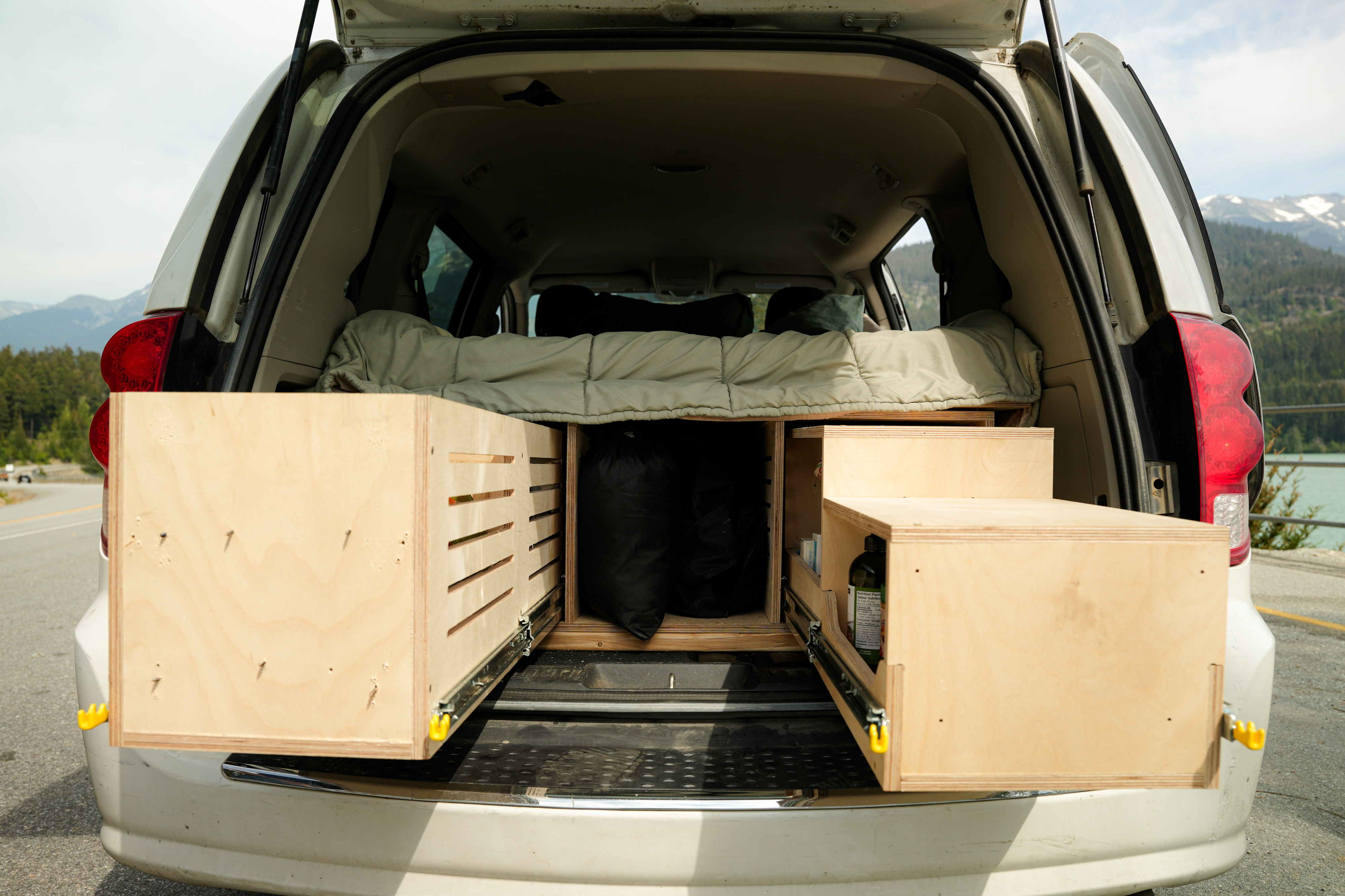 Inside an RV rental campervan: custom wooden storage drawers and a cozy bed setup, perfect for road trips.. Dodge B Van 2017