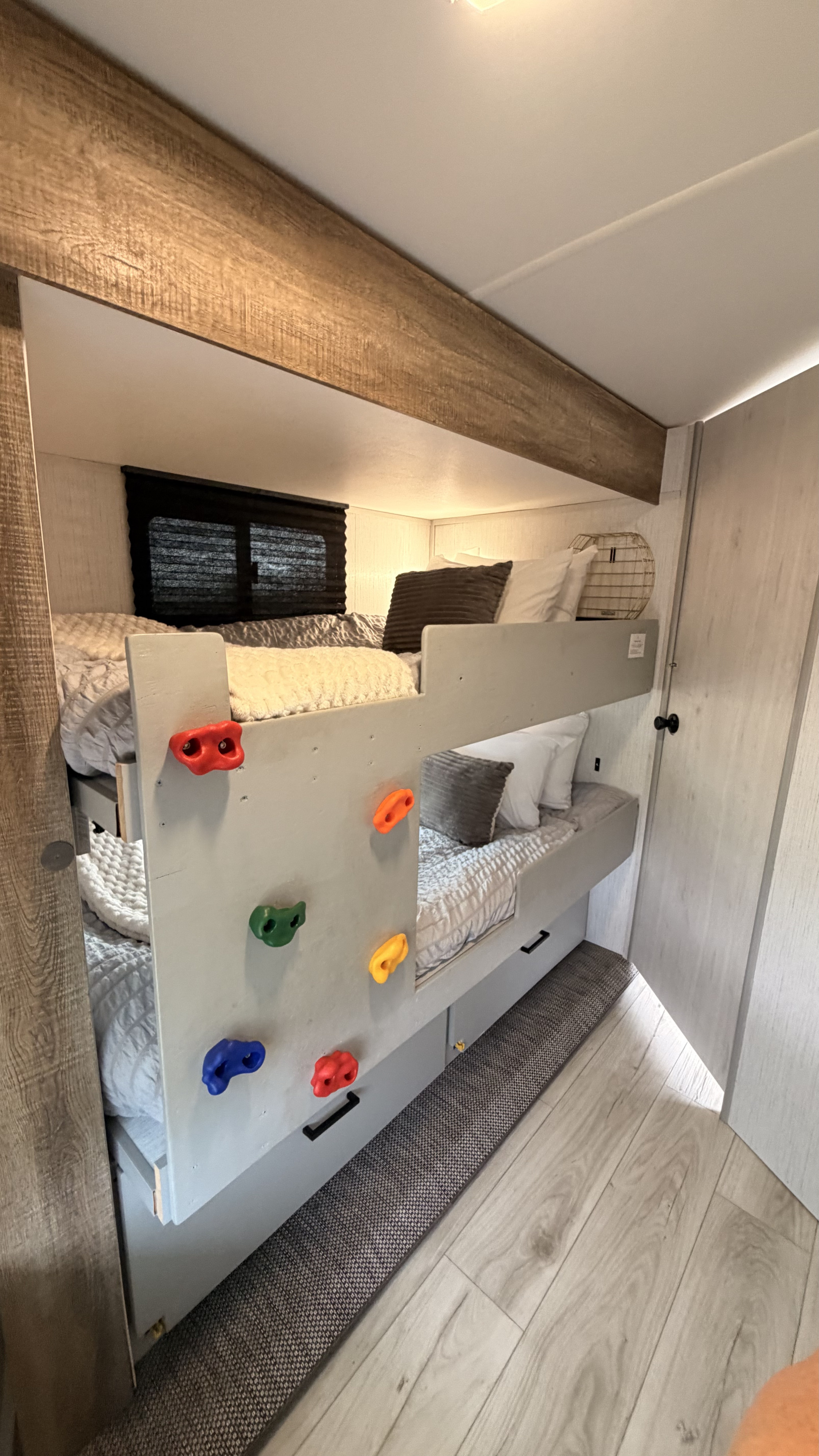 Cozy RV rental bunk beds feature colorful climbing holds on the side panel, comfy bedding, and storage drawers below. Ideal for family trips.. Heartland RVs North Trail 2022