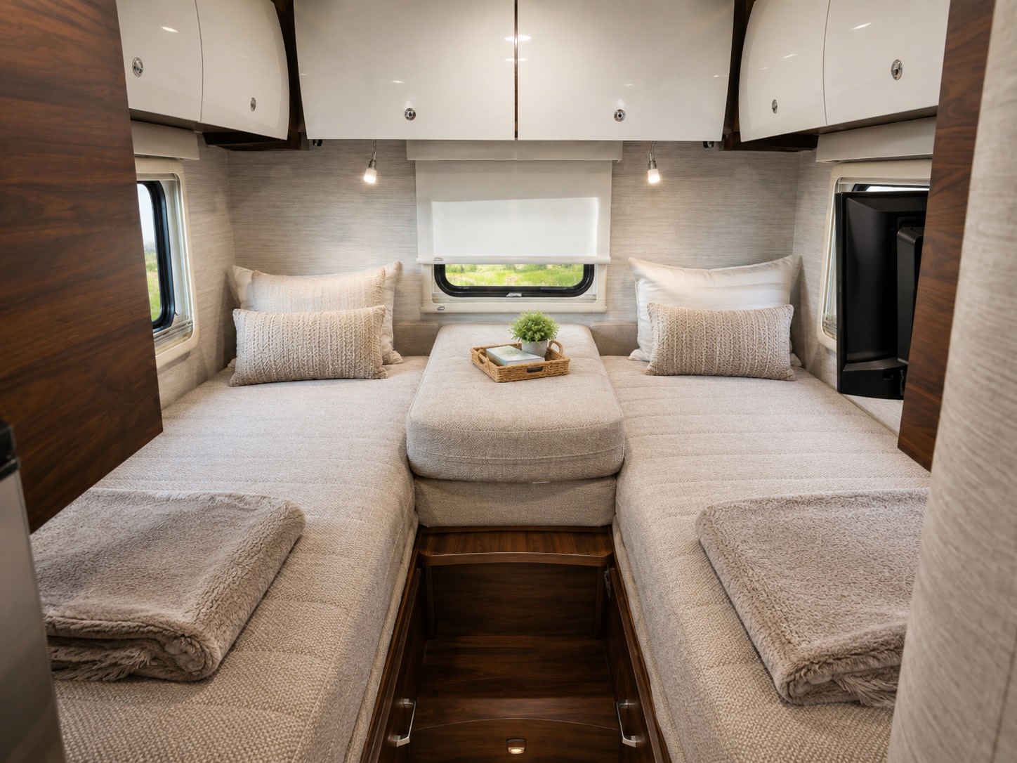 This cozy RV rental interior features twin beds with neutral decor, overhead storage, and a central table, ideal for travel comfort.. Winnebago View 2021