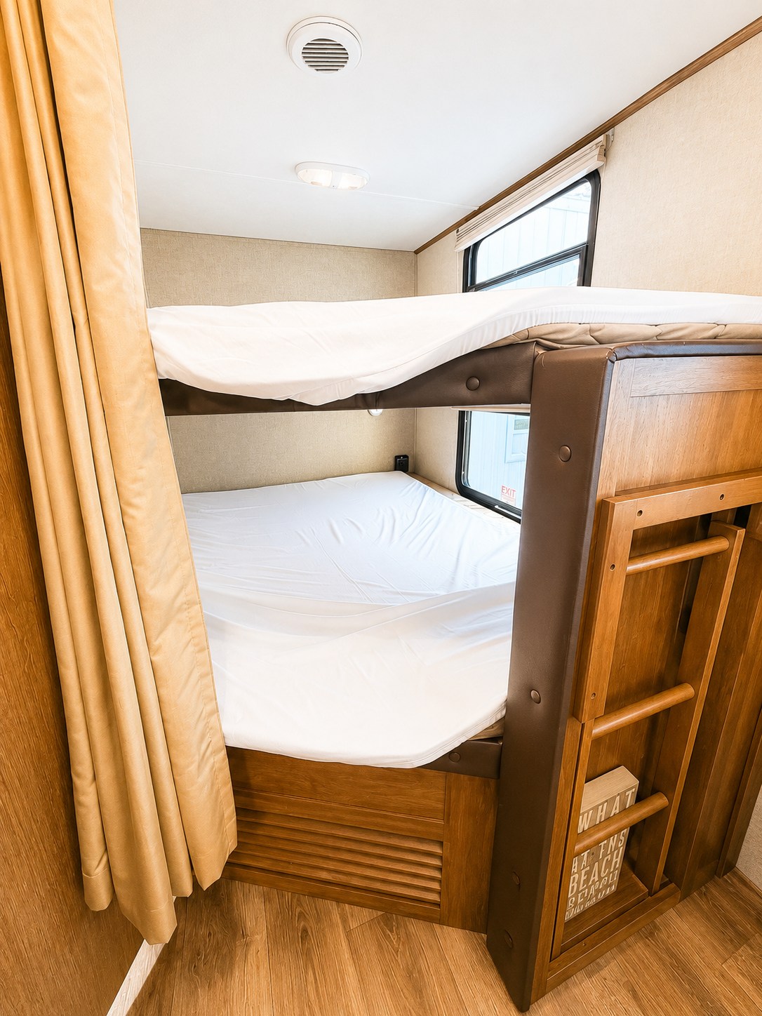 Cozy bunk beds inside an RV rental, complete with white sheets, wooden frames, and a ladder for comfortable sleep.. Keystone Sprinter 2014