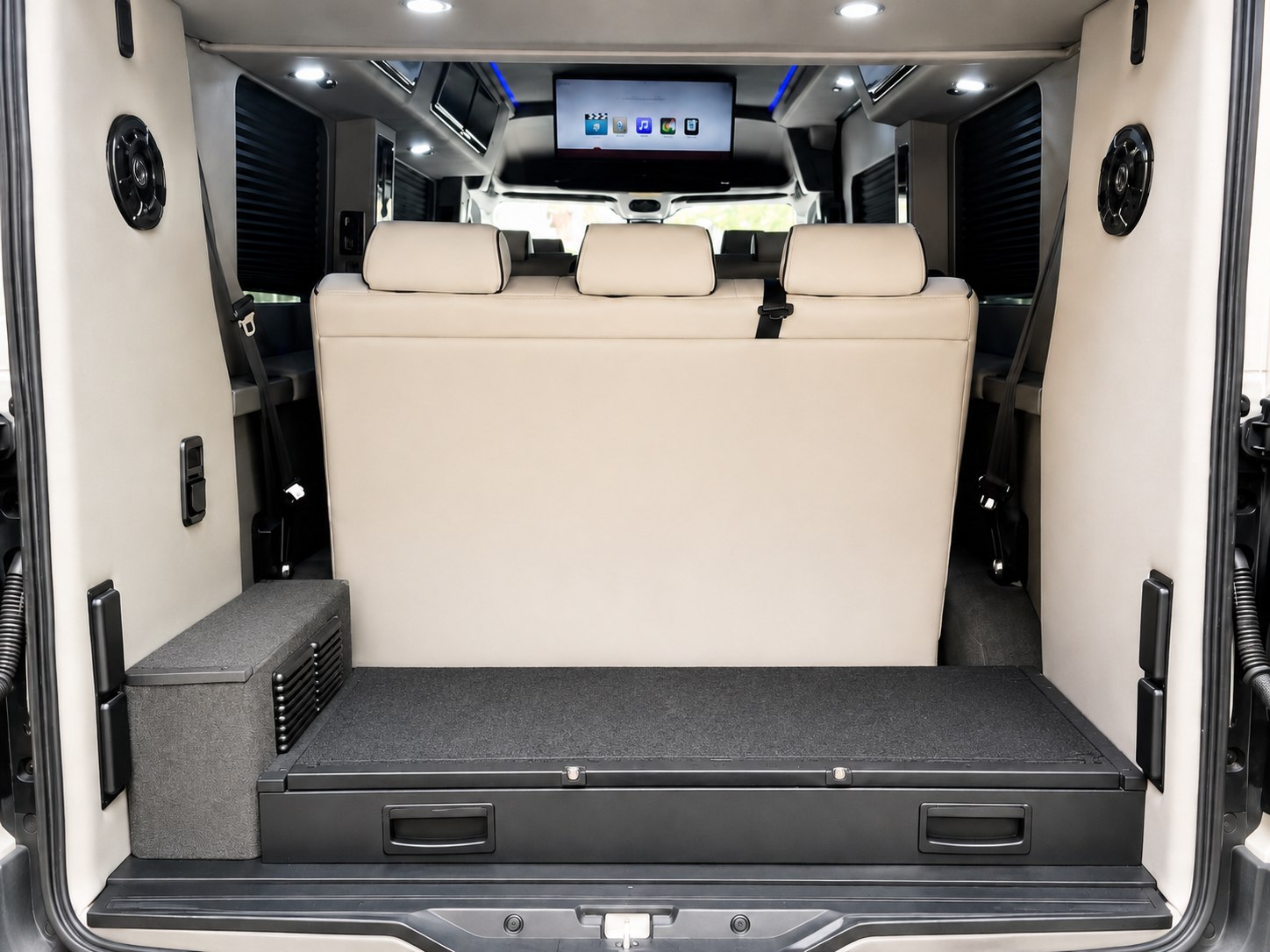 Inside a premium RV rental van: cream bench seating, overhead entertainment, and integrated rear storage area.. Ford Transit Custom 2017