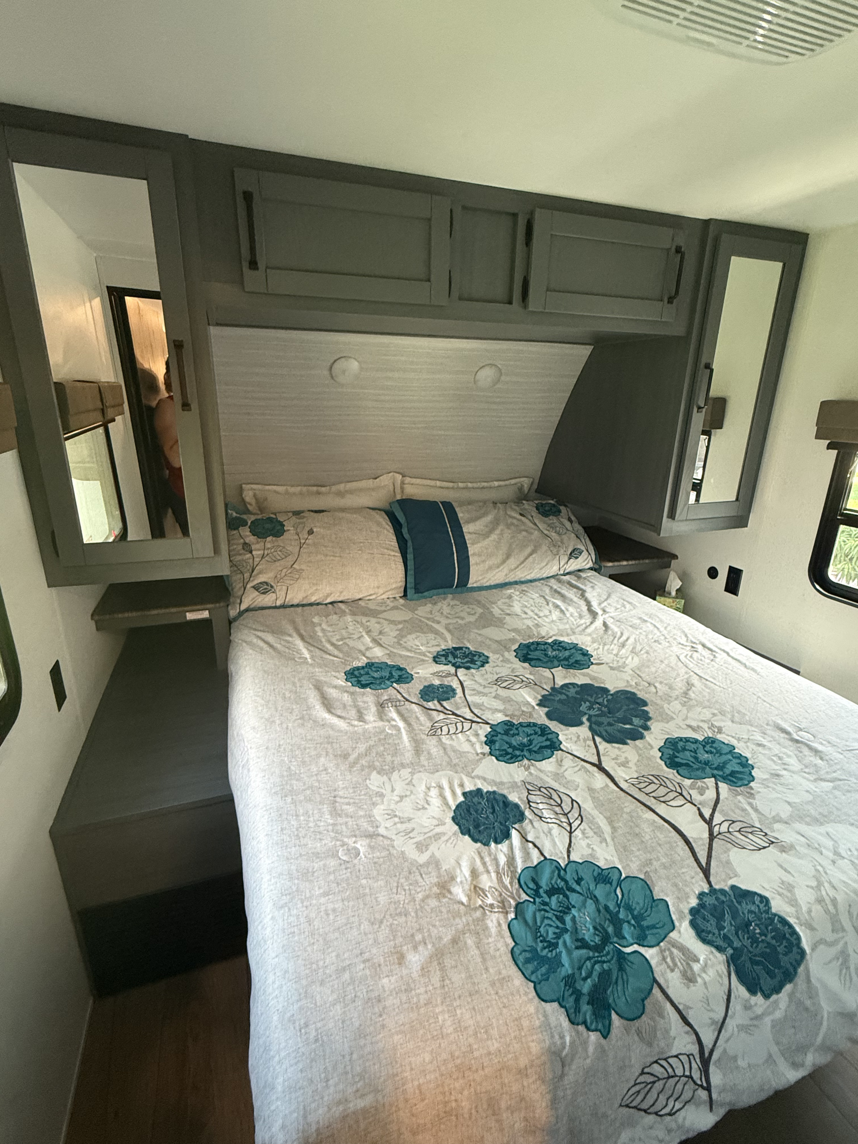 Cozy RV rental bedroom with floral bedding, overhead storage cabinets, mirrored wardrobes, and side shelves.. Forest River Palomino Puma 2026