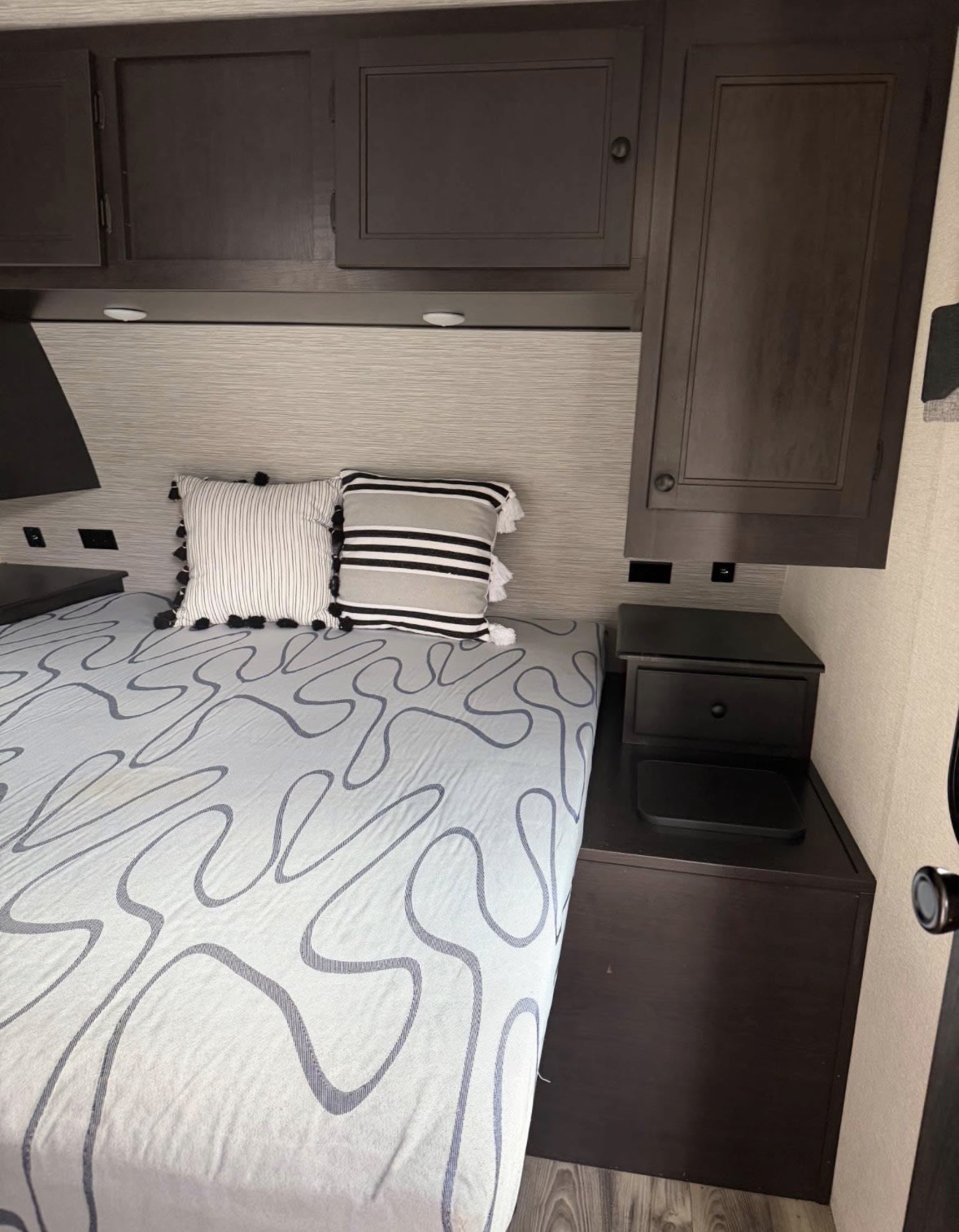 Enjoy this comfortable RV rental's bedroom, featuring overhead cabinets, a cozy bed, and a functional nightstand.. Starcraft Super Lite 2022