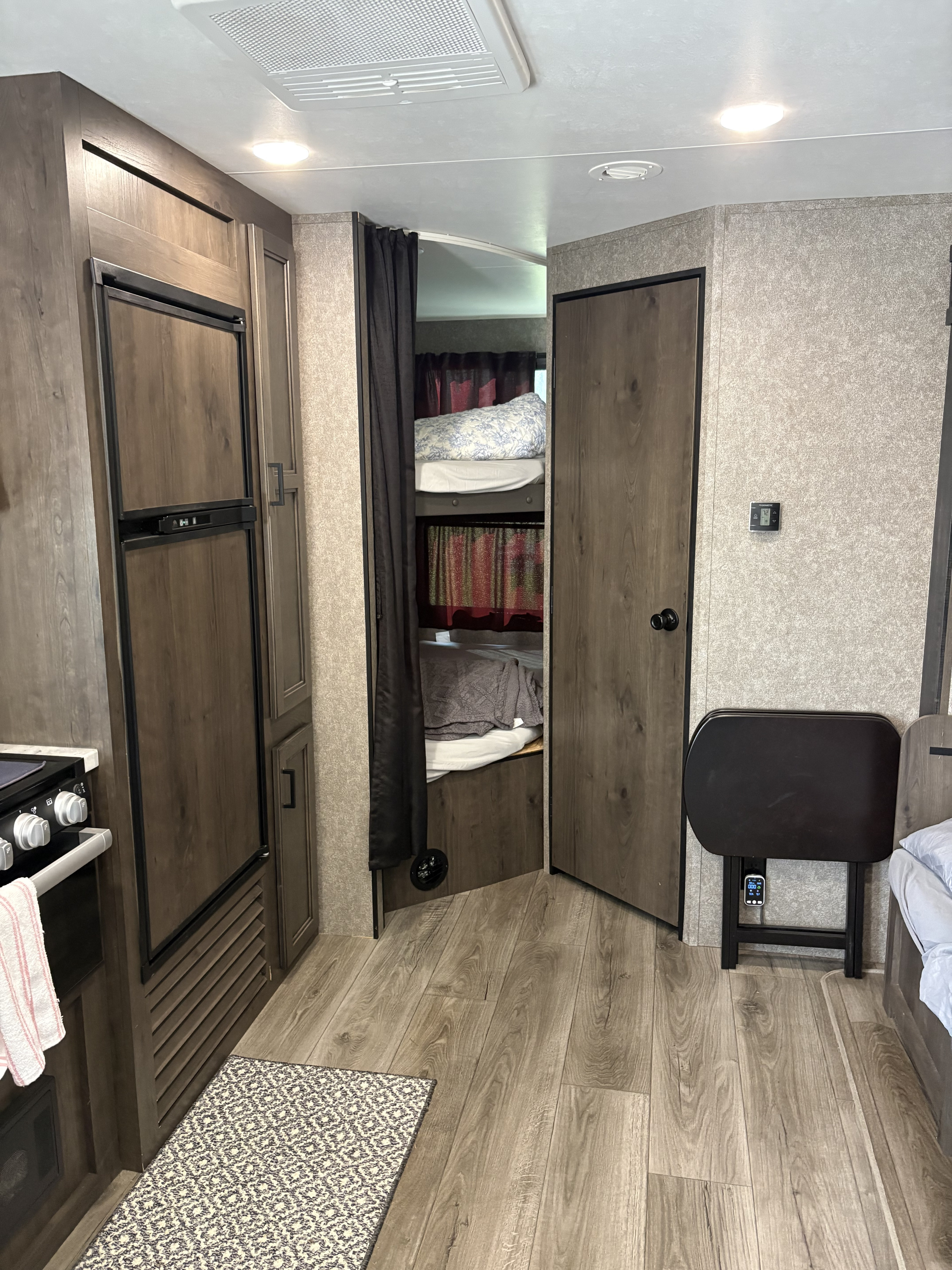 Cozy RV rental interior with kitchen, wood-paneled fridge, bunk beds, and a convenient fold-down table.. Starcraft Autumn Ridge 2021