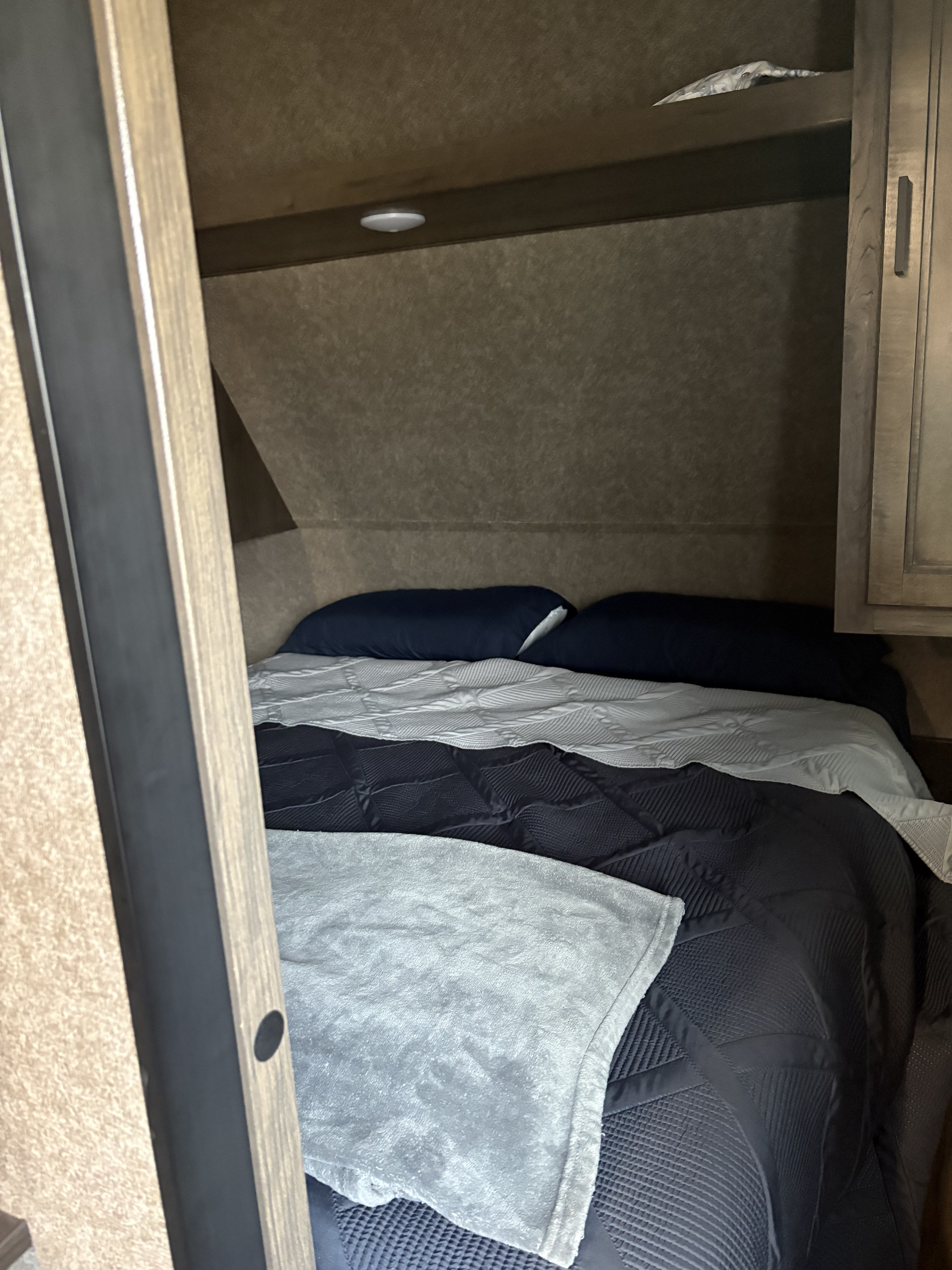 Cozy RV rental bedroom with dark blue bedding and soft blankets, perfect for comfortable travel.. Starcraft Autumn Ridge 2021
