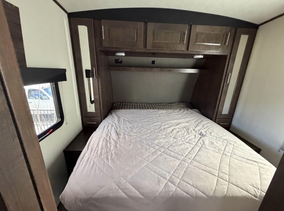 RV rental bedroom with a cozy bed, overhead cabinets, and a window. Compact and functional sleeping area.. Cruiser Rv Corp Stryker 2019