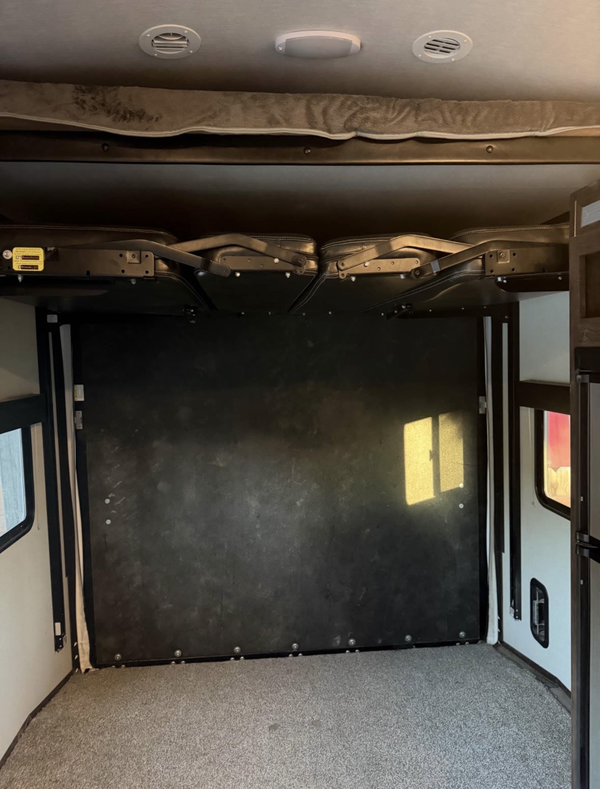 RV rental interior: Upper bunk bed and folded seating, revealing the open floor of a camper's cargo area.. Cruiser Rv Corp Stryker 2019