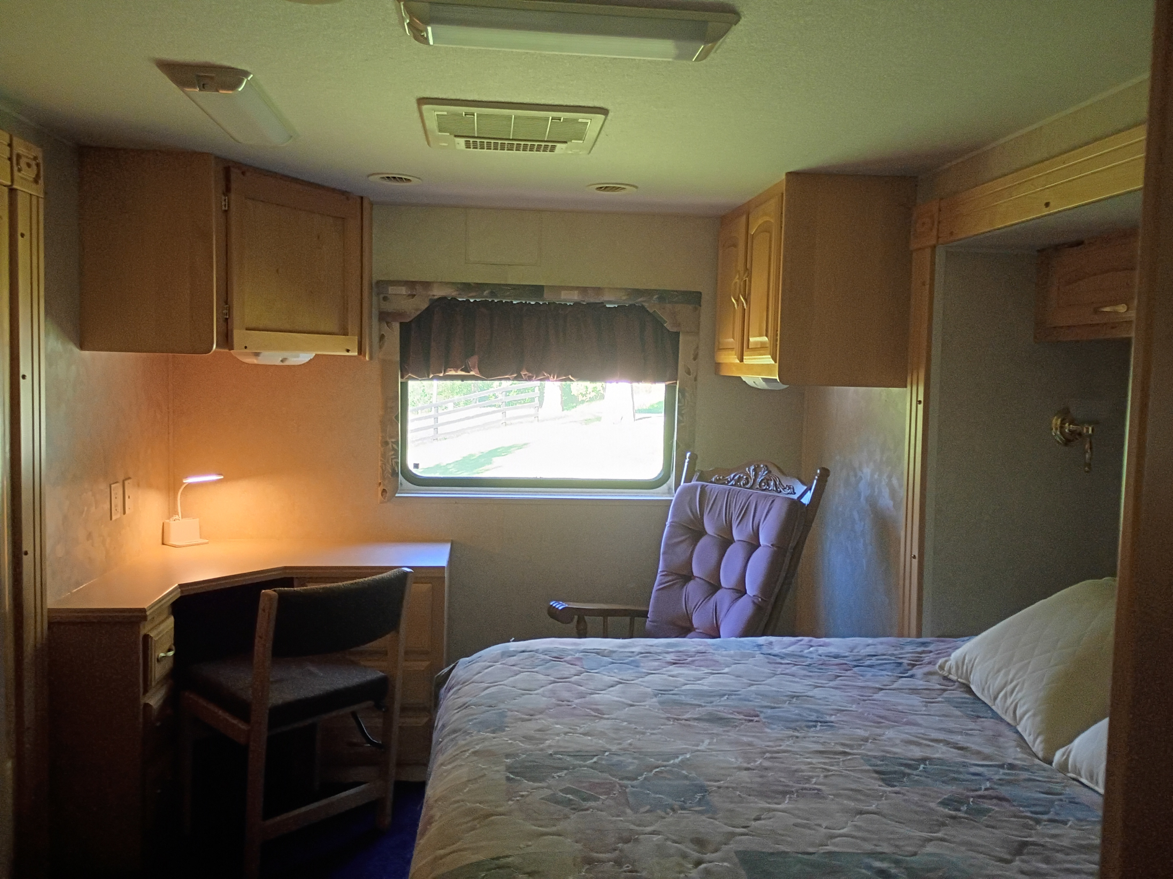 Cozy RV rental bedroom features a comfy bed, desk, chair, and window view. Perfect for your next adventure.. Georgie Boy Cruise-Master 2003