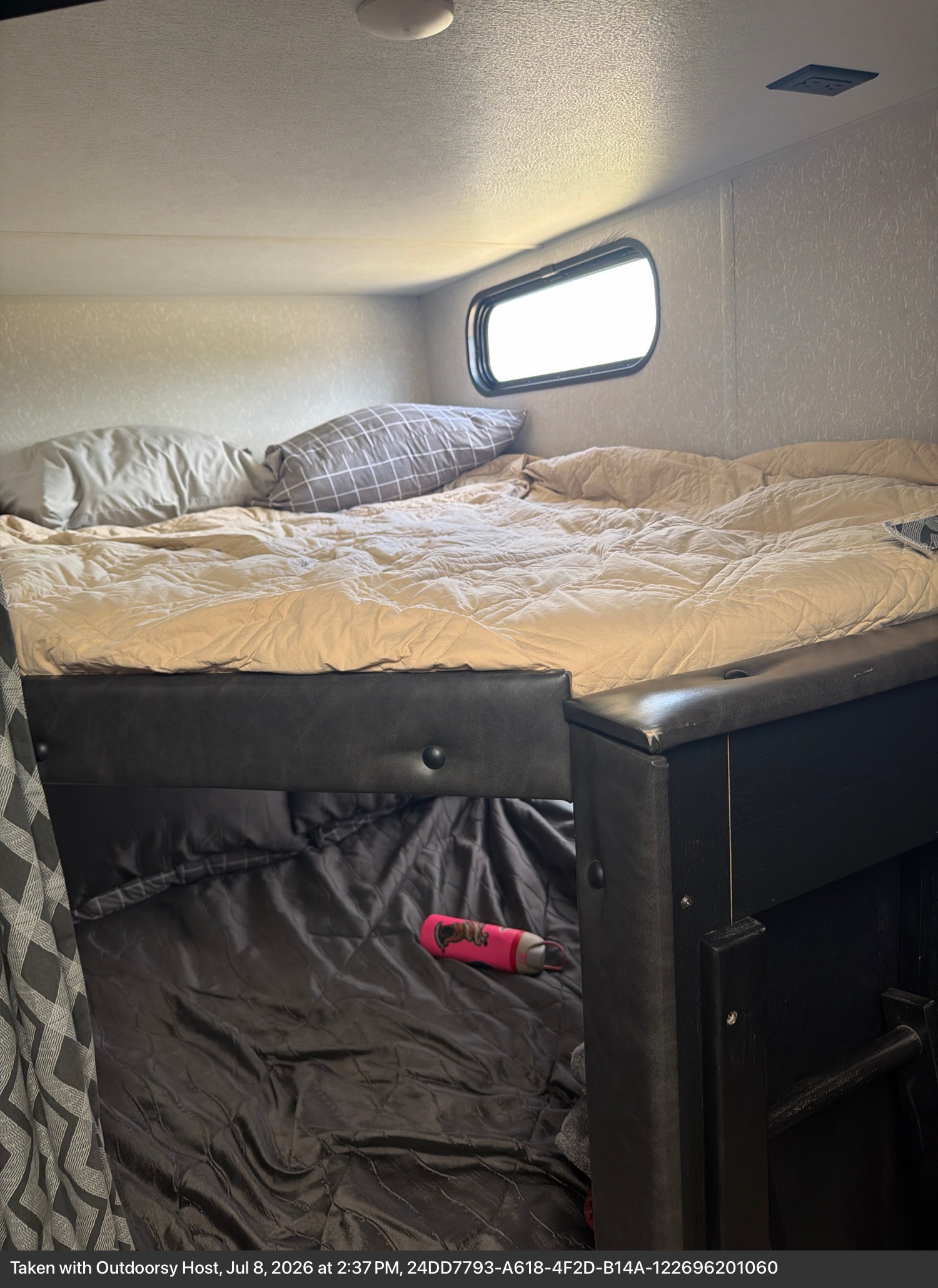 Cozy RV rental bunk beds. Top bed with light bedding, bottom with dark. Small window brightens this comfortable sleeping area.. Forest River Cherokee 2021