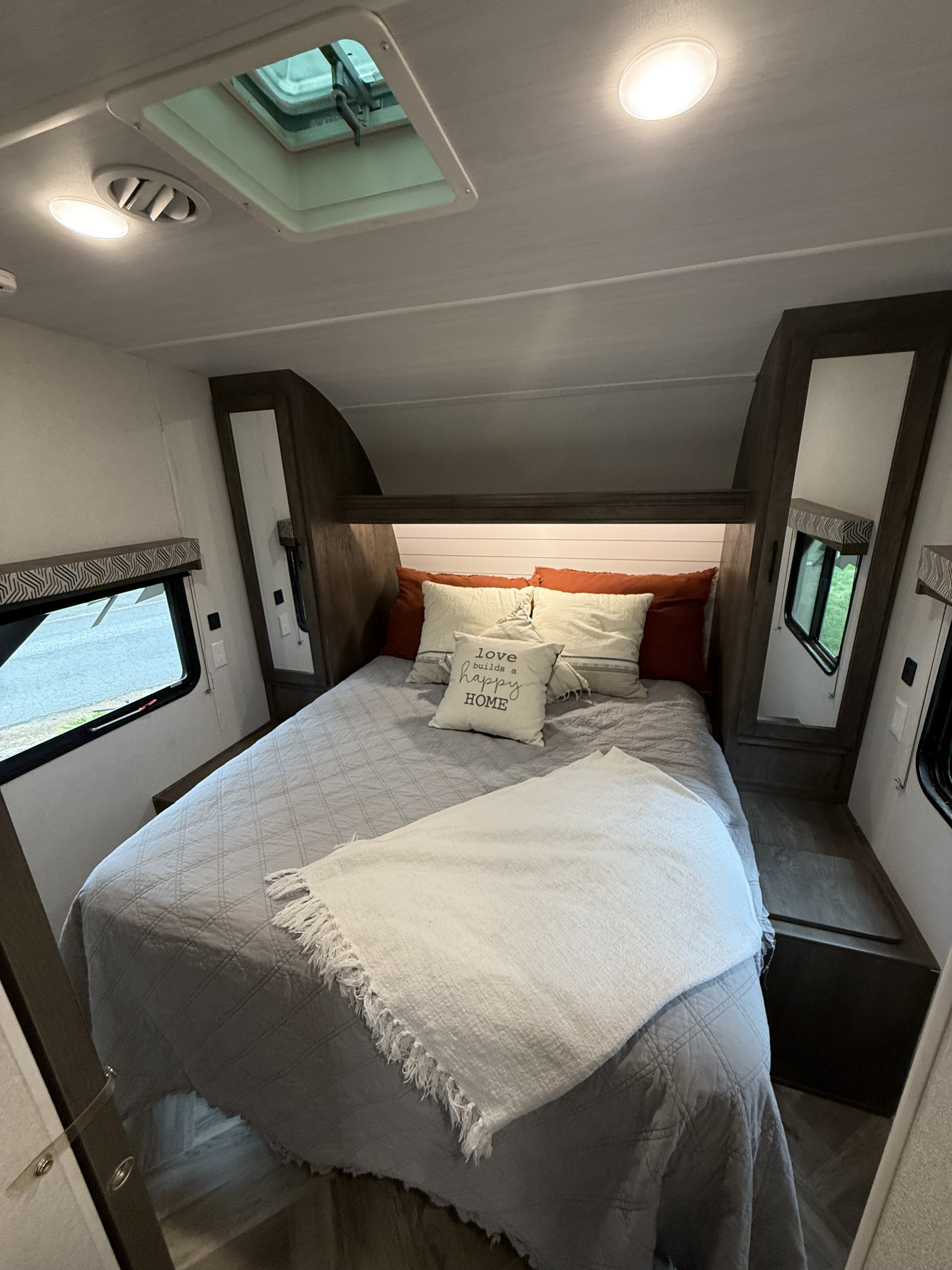 Cozy RV rental bedroom with a neatly made bed, throw blanket, windows, and overhead lights, providing a comfortable space.. Forest River Stealth 2020