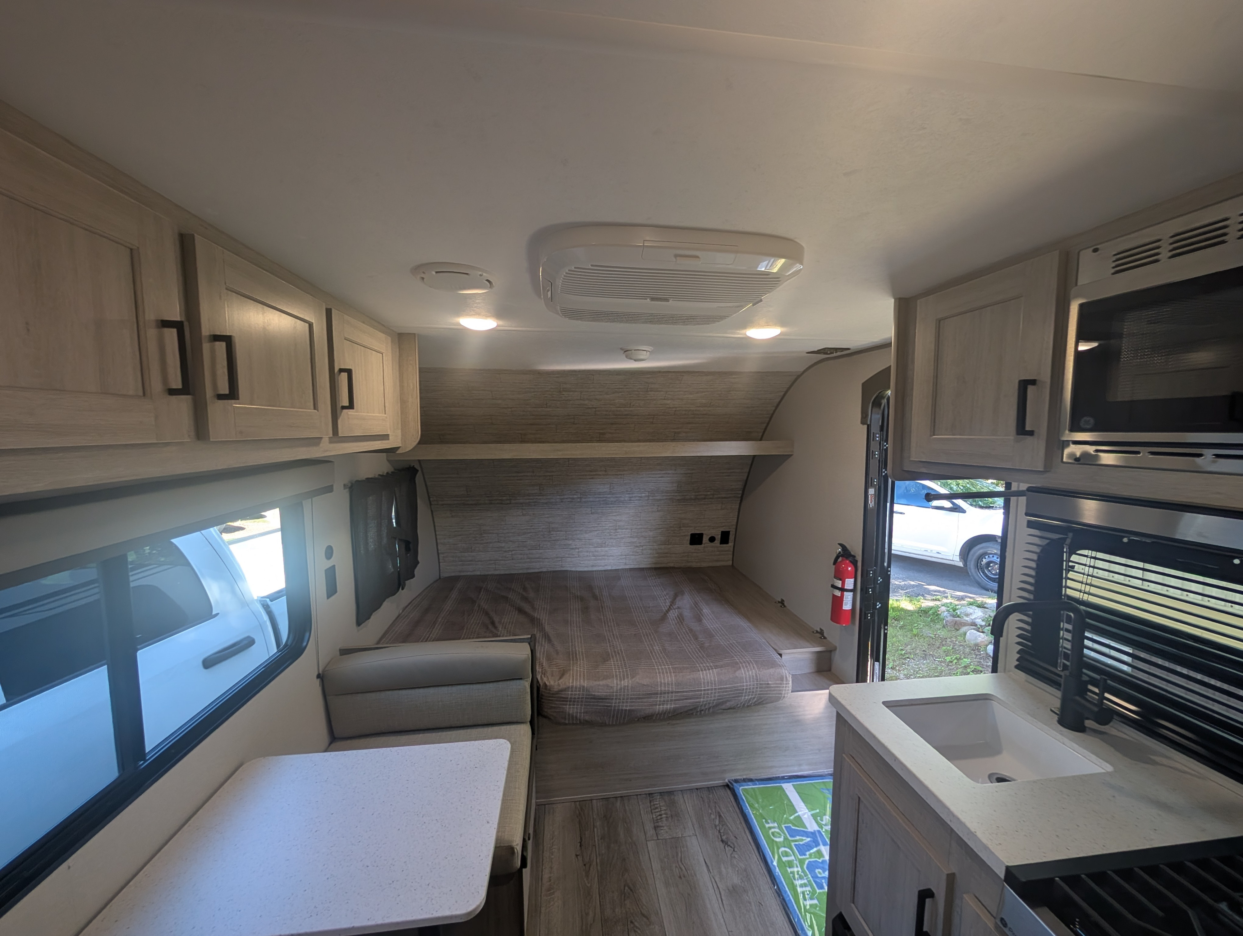 RV rental interior view: features a cozy bed, dinette, kitchen with sink and microwave, and overhead storage cabinets.. Coachman Catilina 16bhx 2026