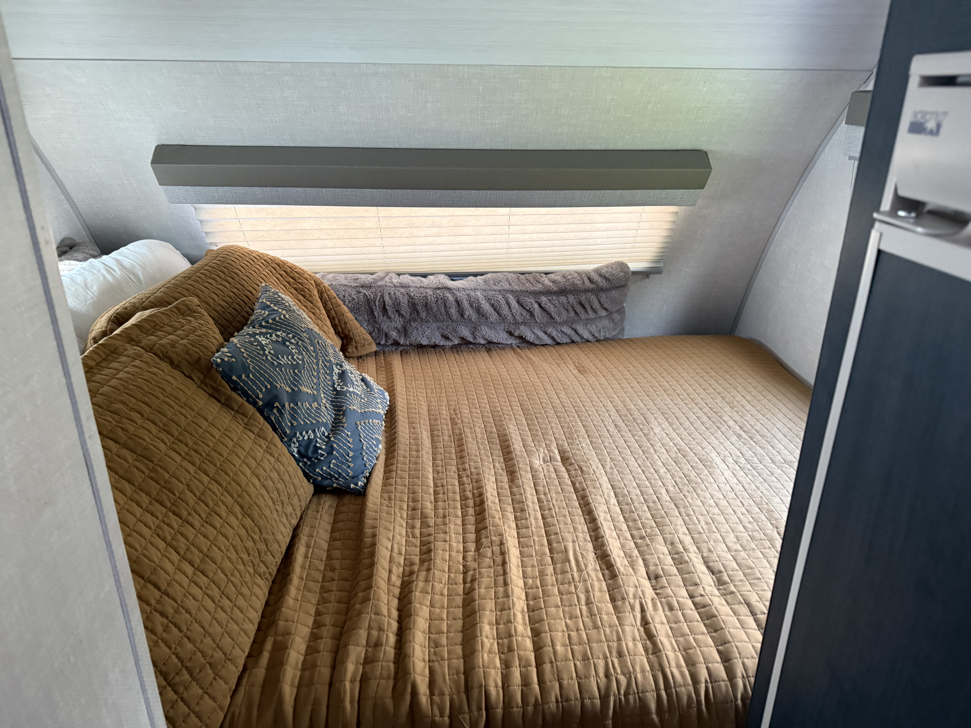 Cozy RV rental bedroom with a comfortable bed, brown quilted bedspread, and decorative pillows, perfect for your next adventure.. R-Pod R-Pod Trailer 2023