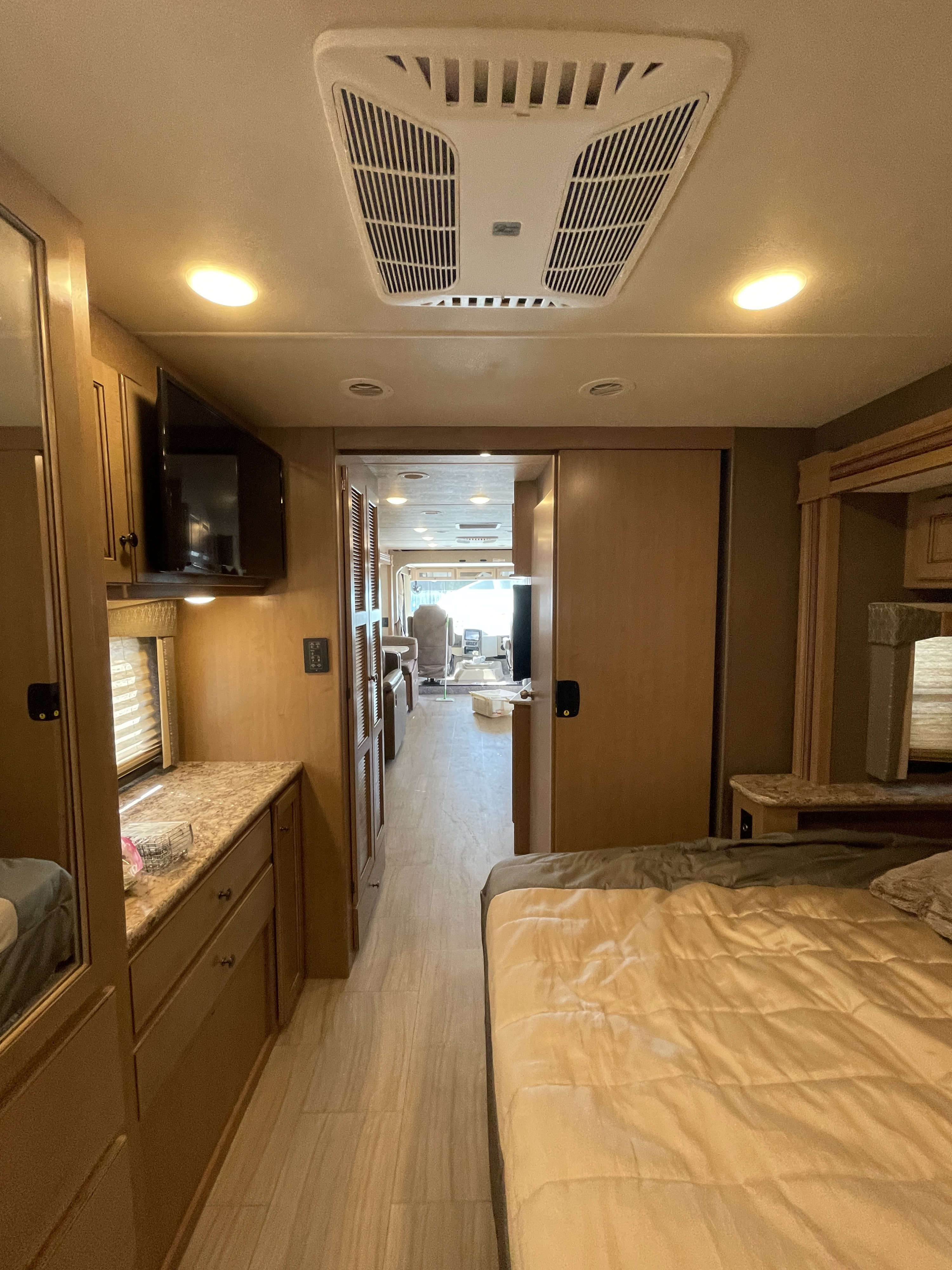 RV rental interior: View from bedroom towards front cabin, featuring a bed, hallway, TV, and AC unit in this mobile home.. Thor Windsport 2019